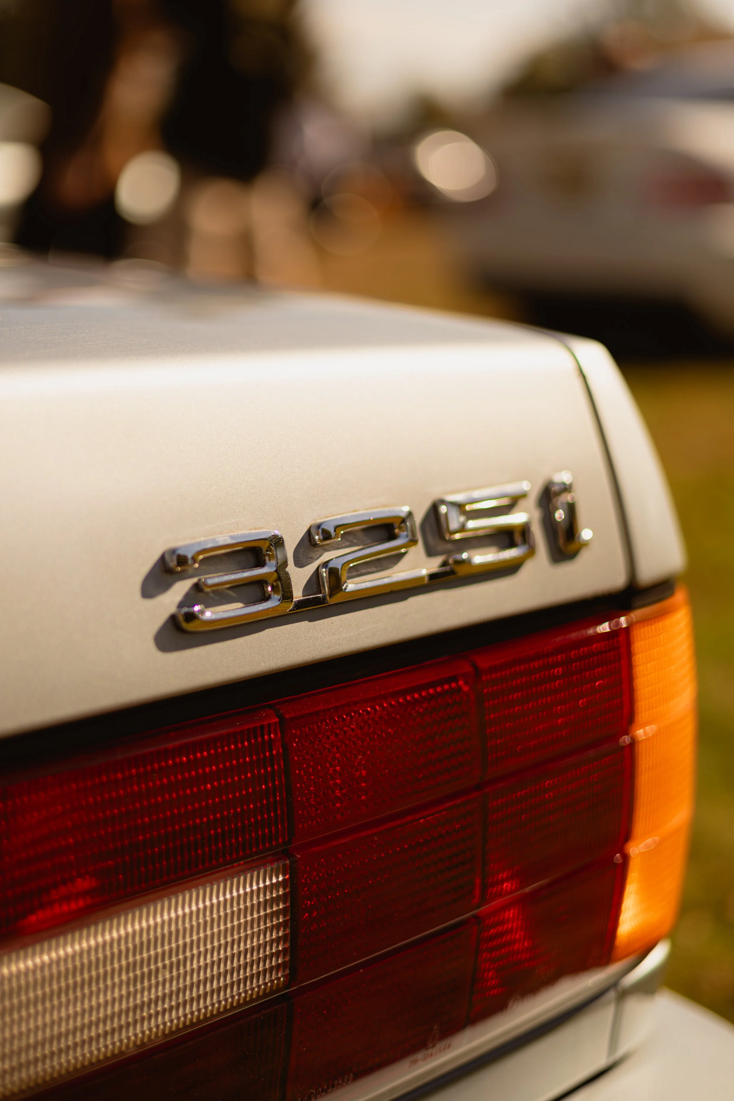 Close-up of the rear of a vintage silver BMW showing the model badge and tail light.