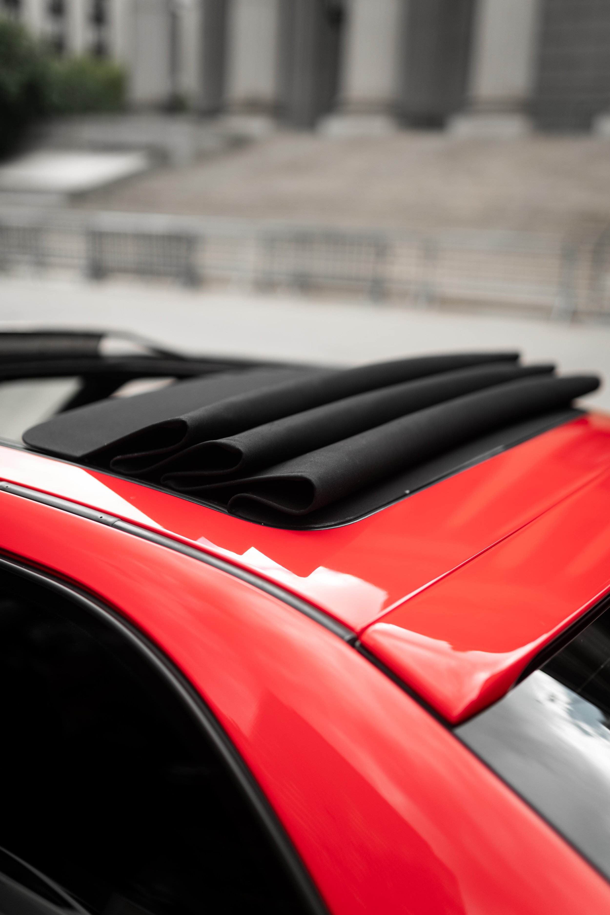 Detail of a soft retractable roof of a red 318ti BMW.
