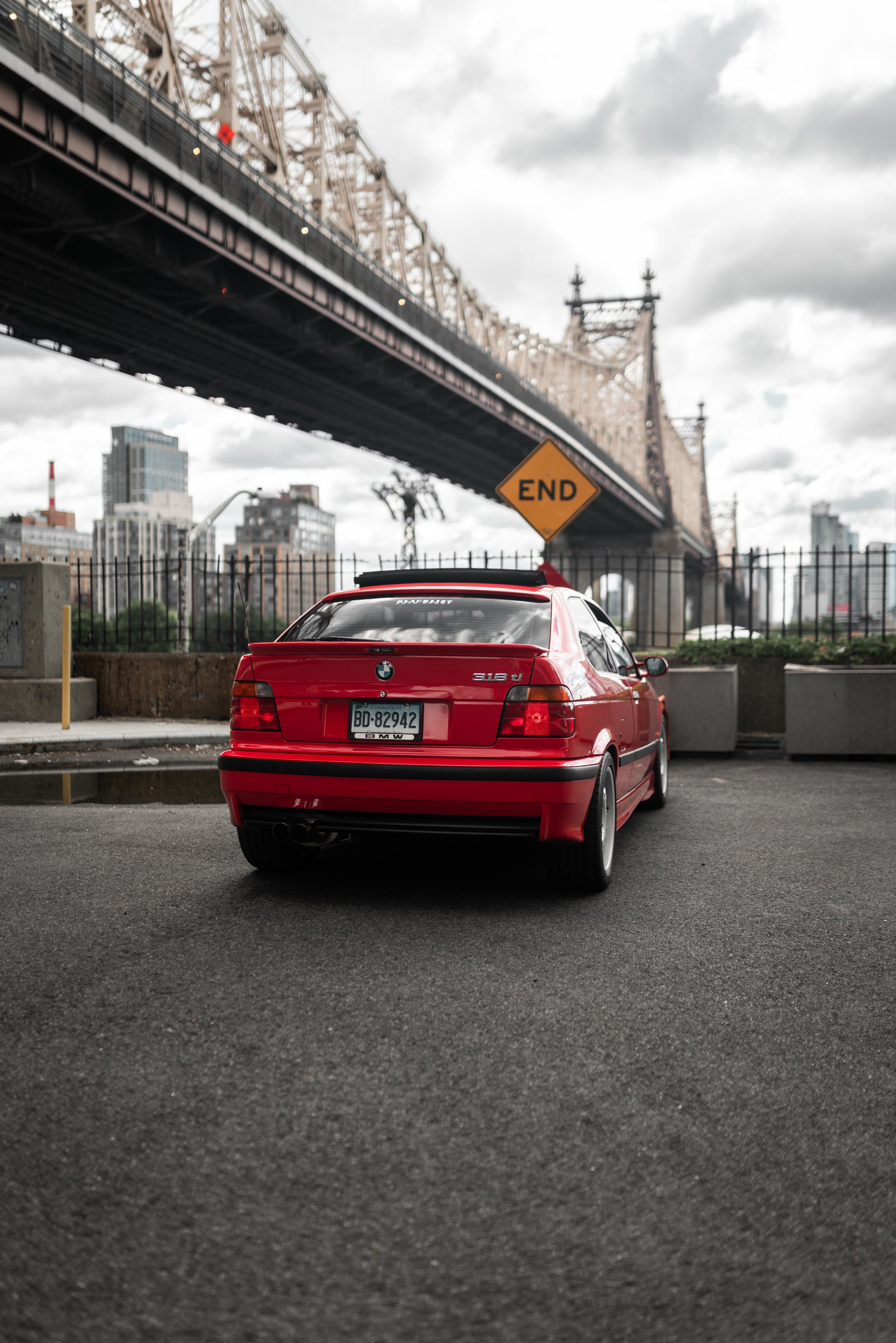 Back of a red 318ti under a bridge in new york city.