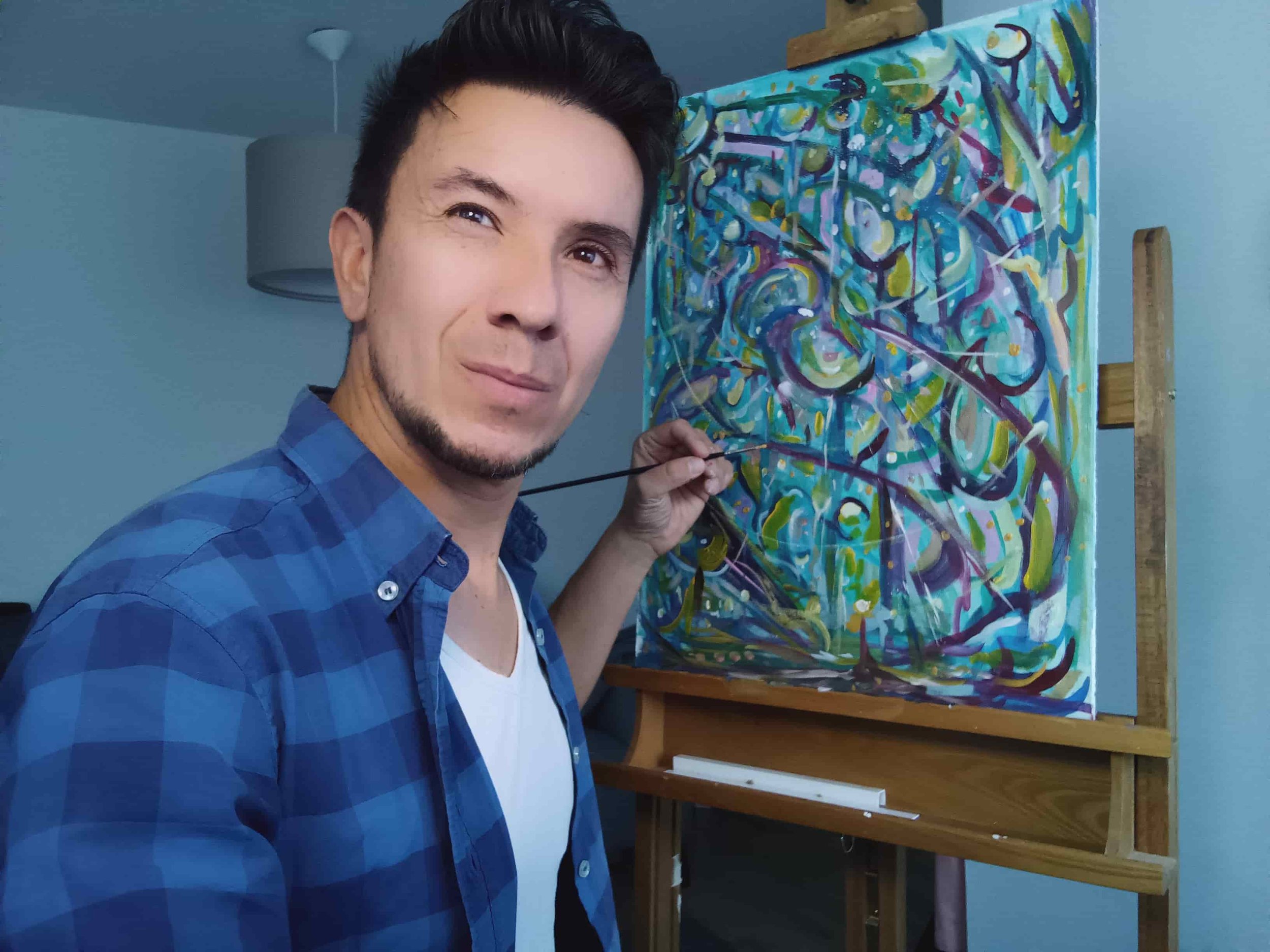 Man die een kleurrijk abstract schilderij met een verfkwast bewerkt in een kamer.