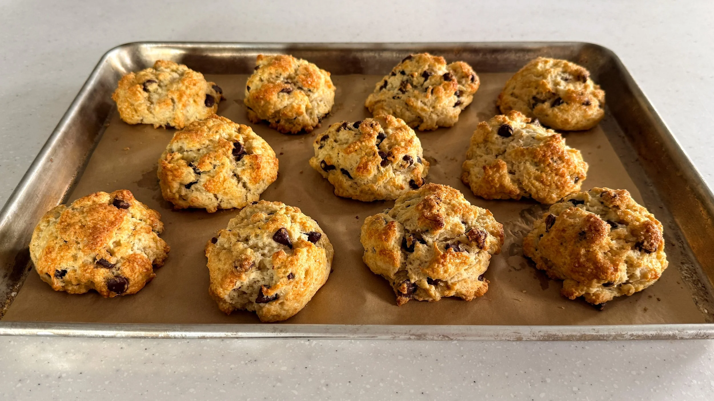 Sheet tray with parchment and chocolate chip scones on top.