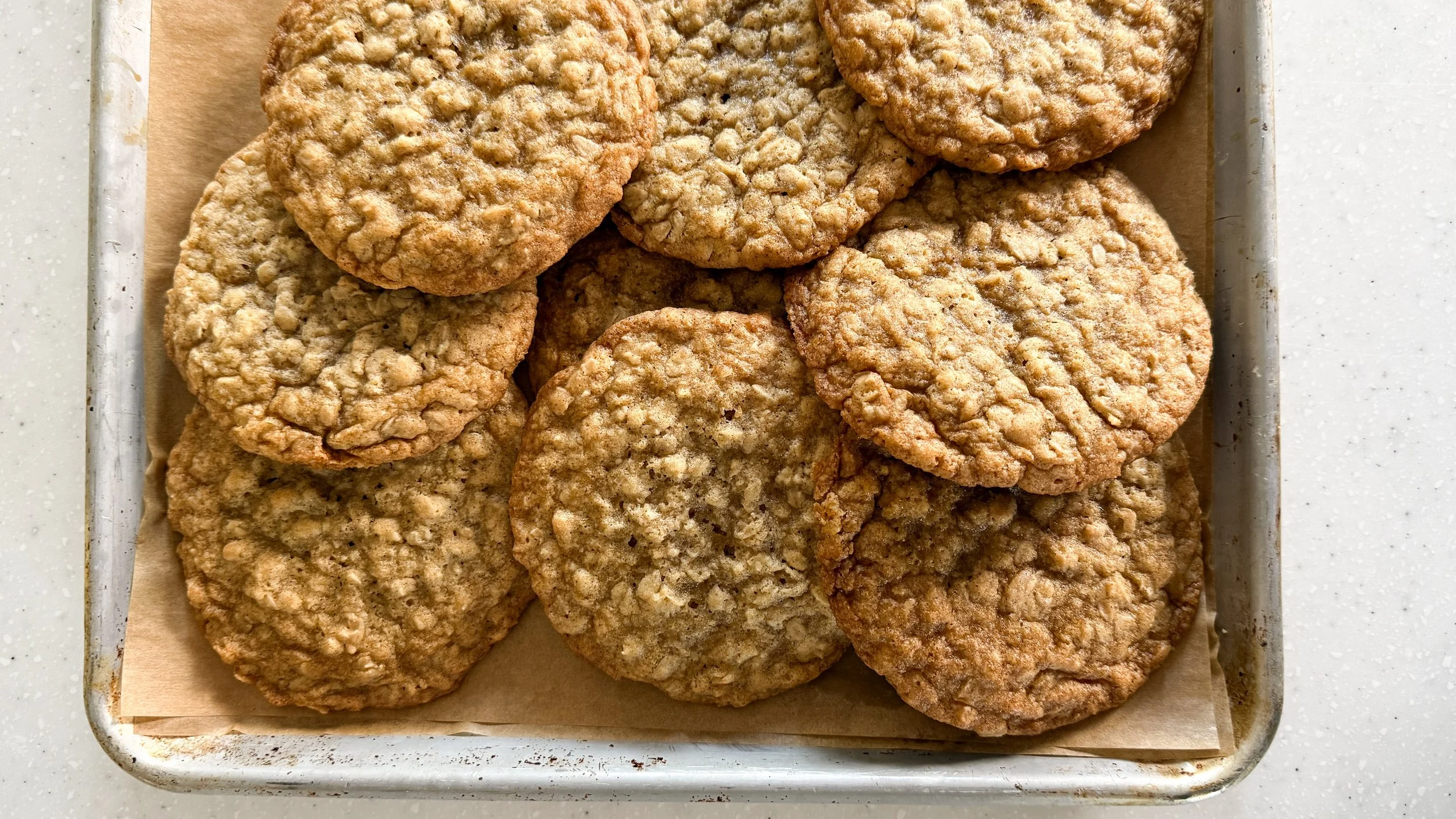 A baking sheet with a pile of cardamom oatmeal cookies.
