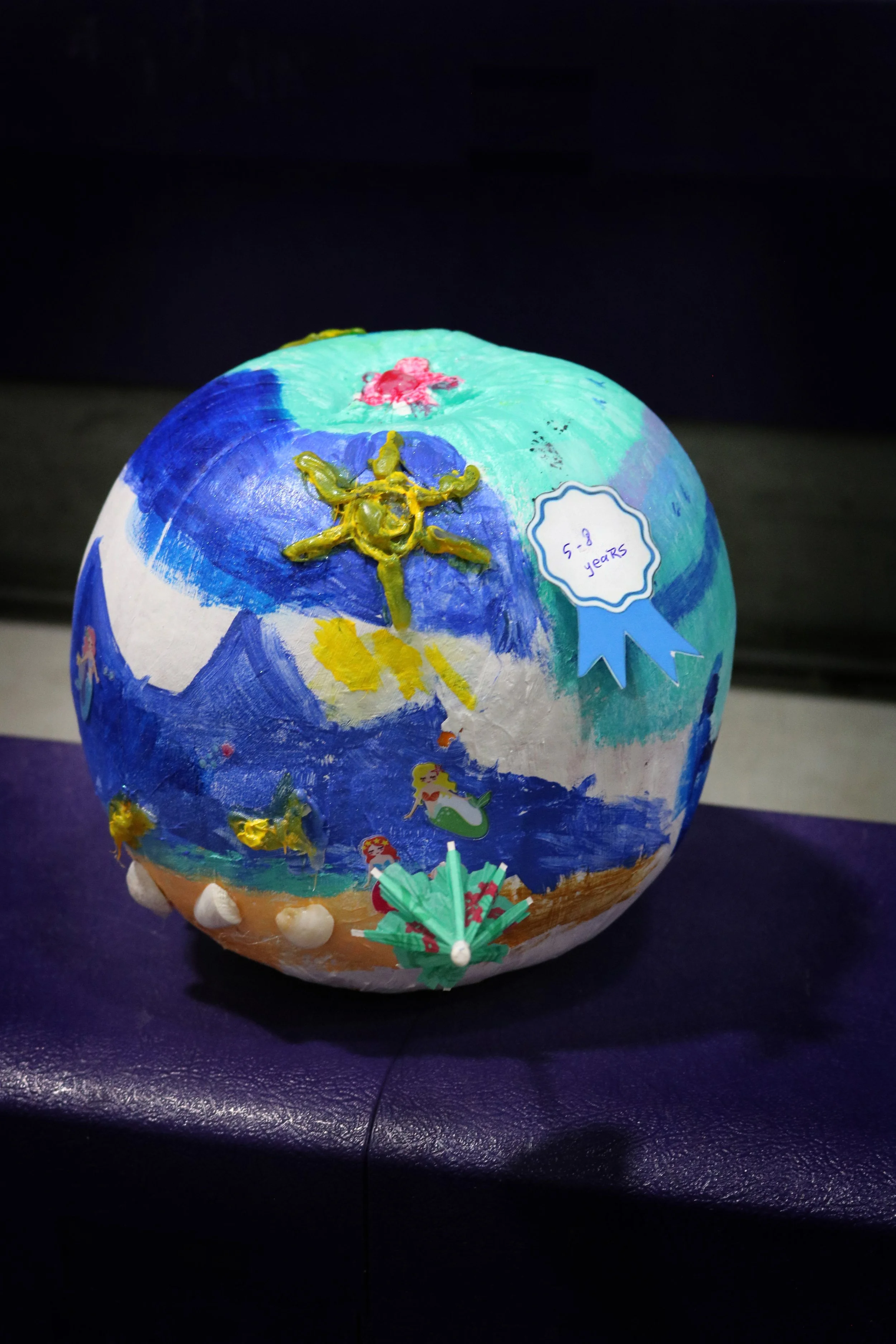 Hand-painted decorated globe with ocean scenes, a yellow starfish, mermaids, and a blue ribbon that says "5-8 years."