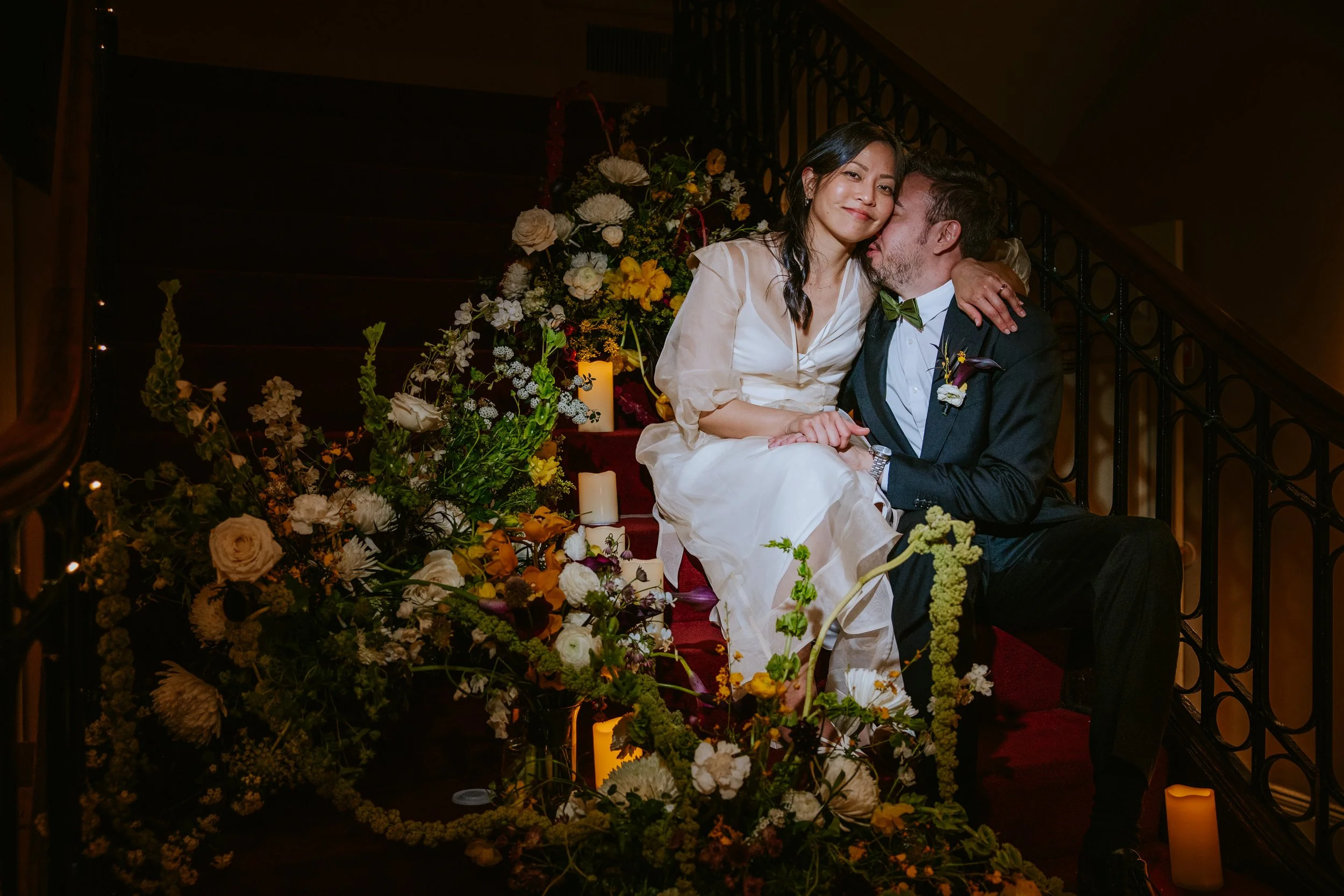 Newly wed couple on staircase surrounded by flowers at the Josephine Butler Parks Center in Washington, D.C. 