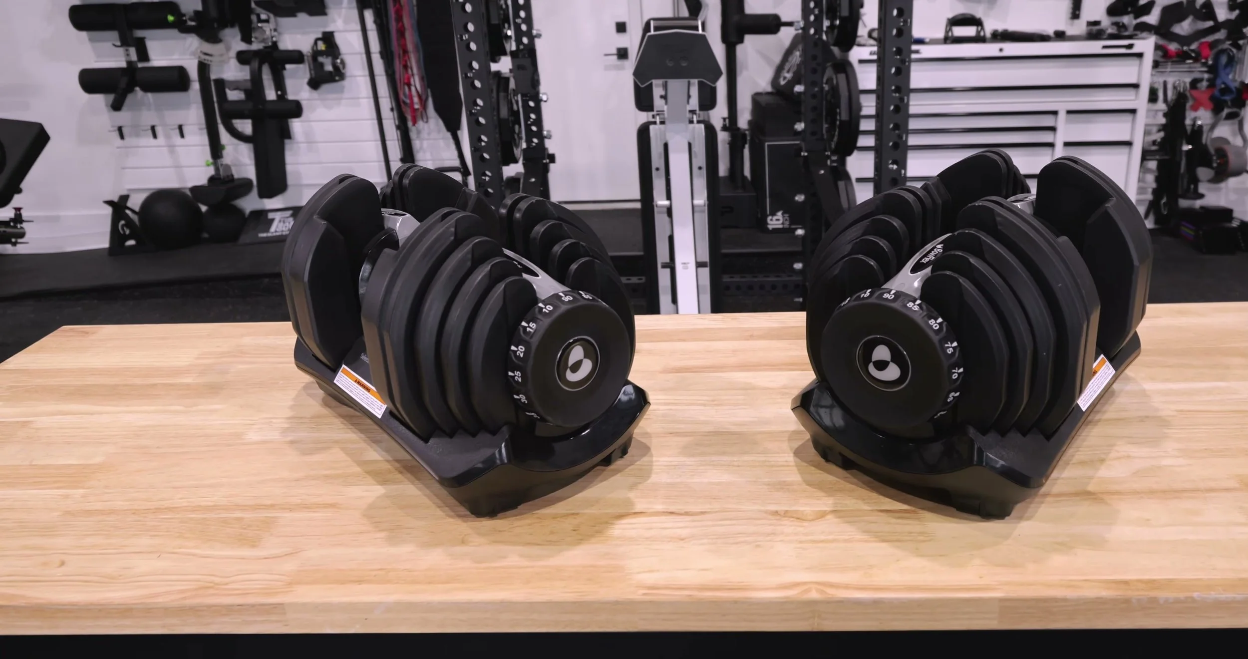 Bowflex SelectTech 1090 adjustable dumbbells resting in their cradles on a gym floor