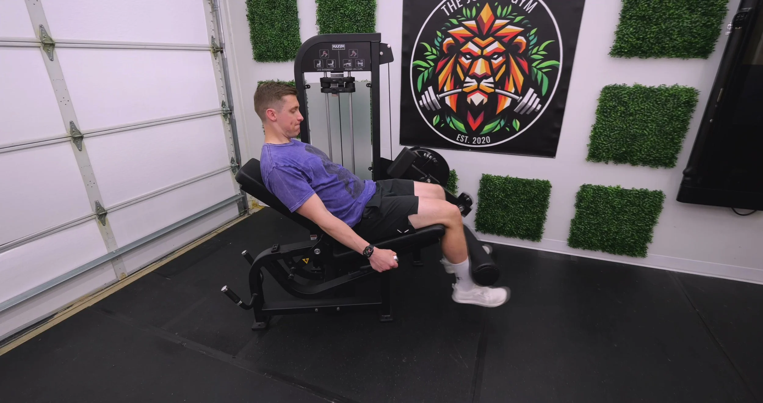 Performing a seated leg extension on the MAXUM LEC3 showing the limited starting angle