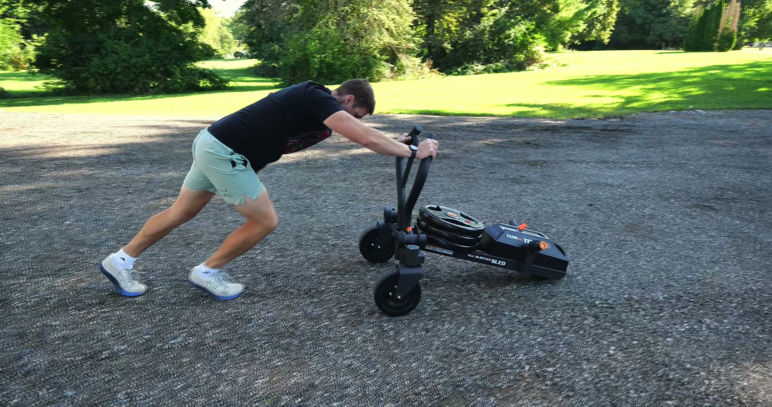 Torque TANK M1S being pushed across loose gravel during an outdoor workout
