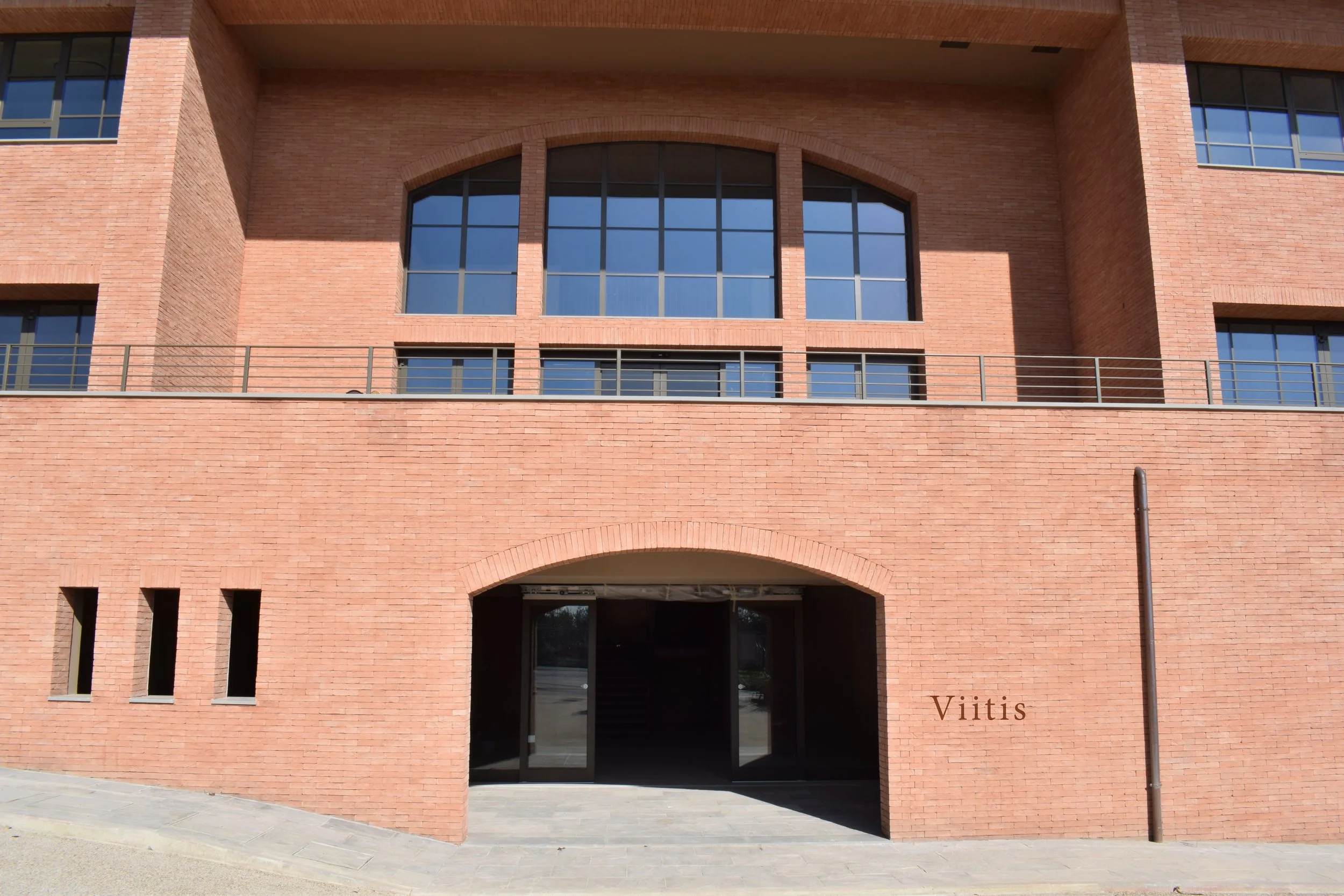 Red brick building facade with arched entrance and “Viitis” signage.