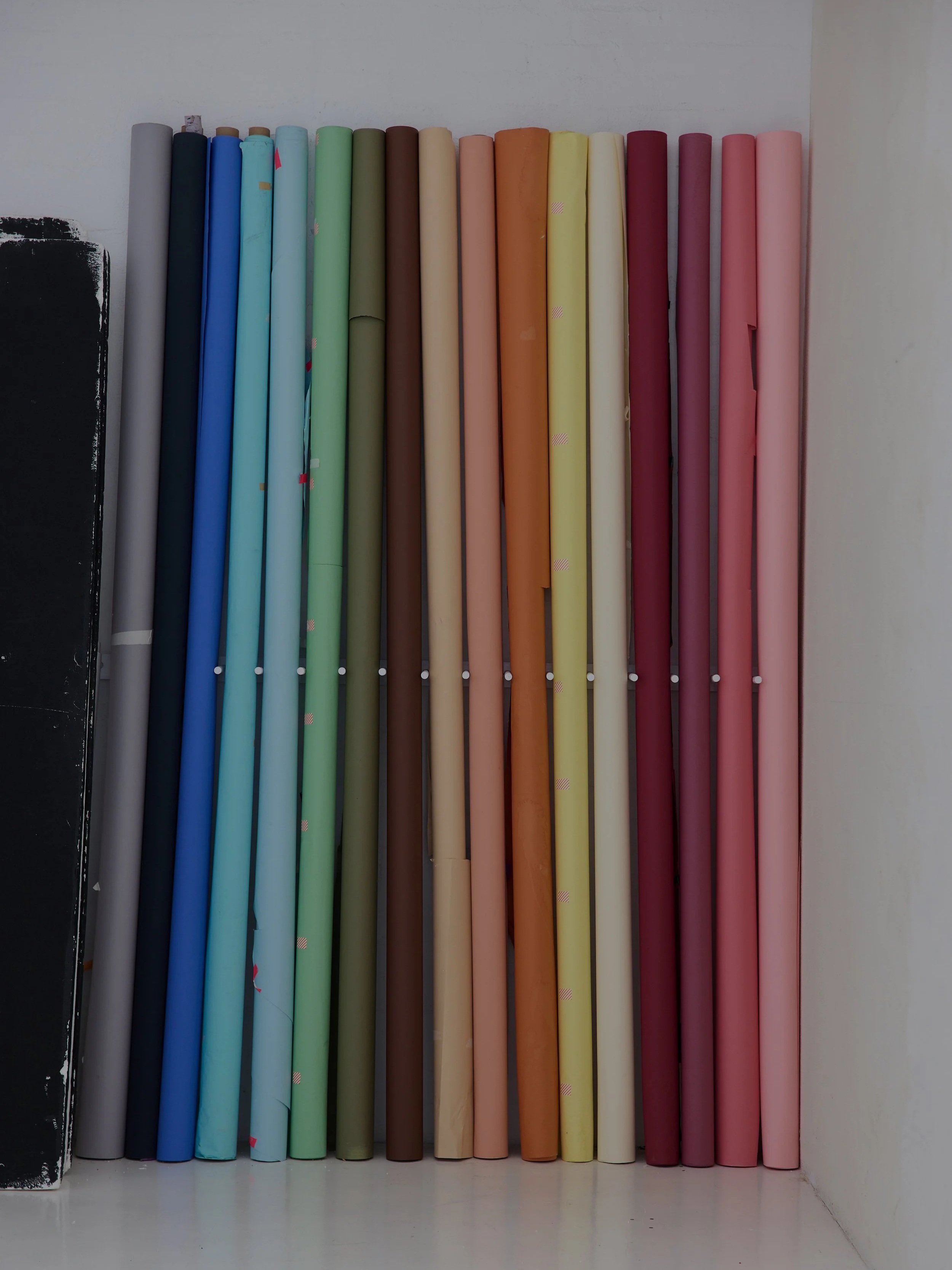 Rolled colourful backdrop paper rolls arranged vertically.