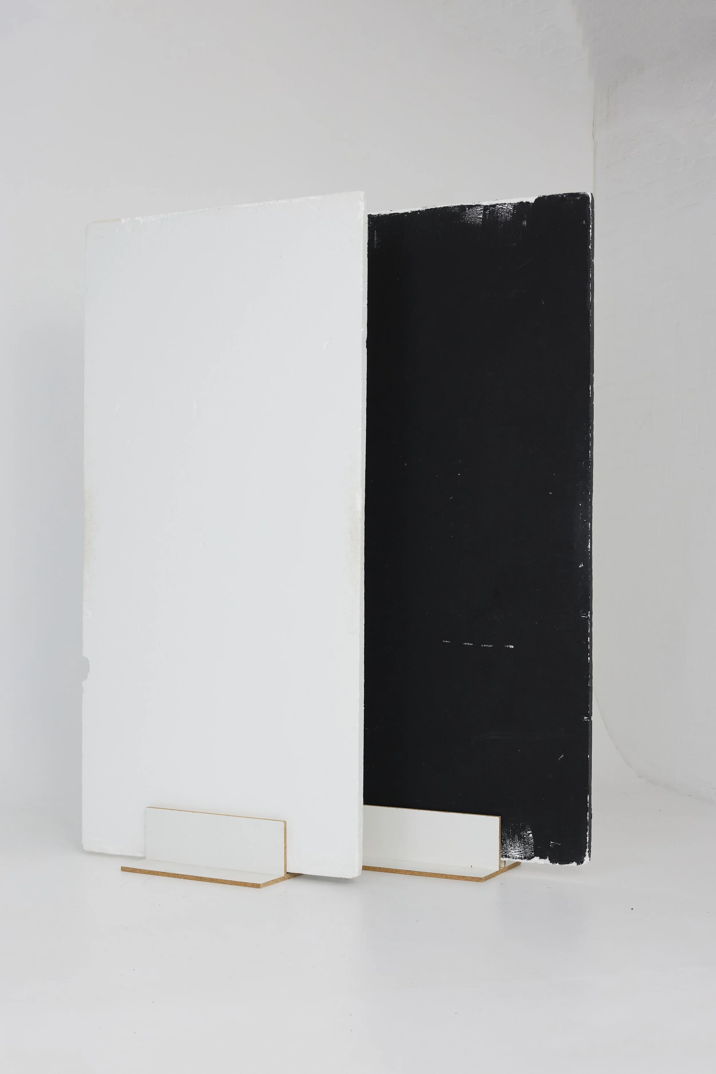 Two rectangular panels, one white and one black, standing side by side on a white surface, with the white panel slightly in front of the black panel.