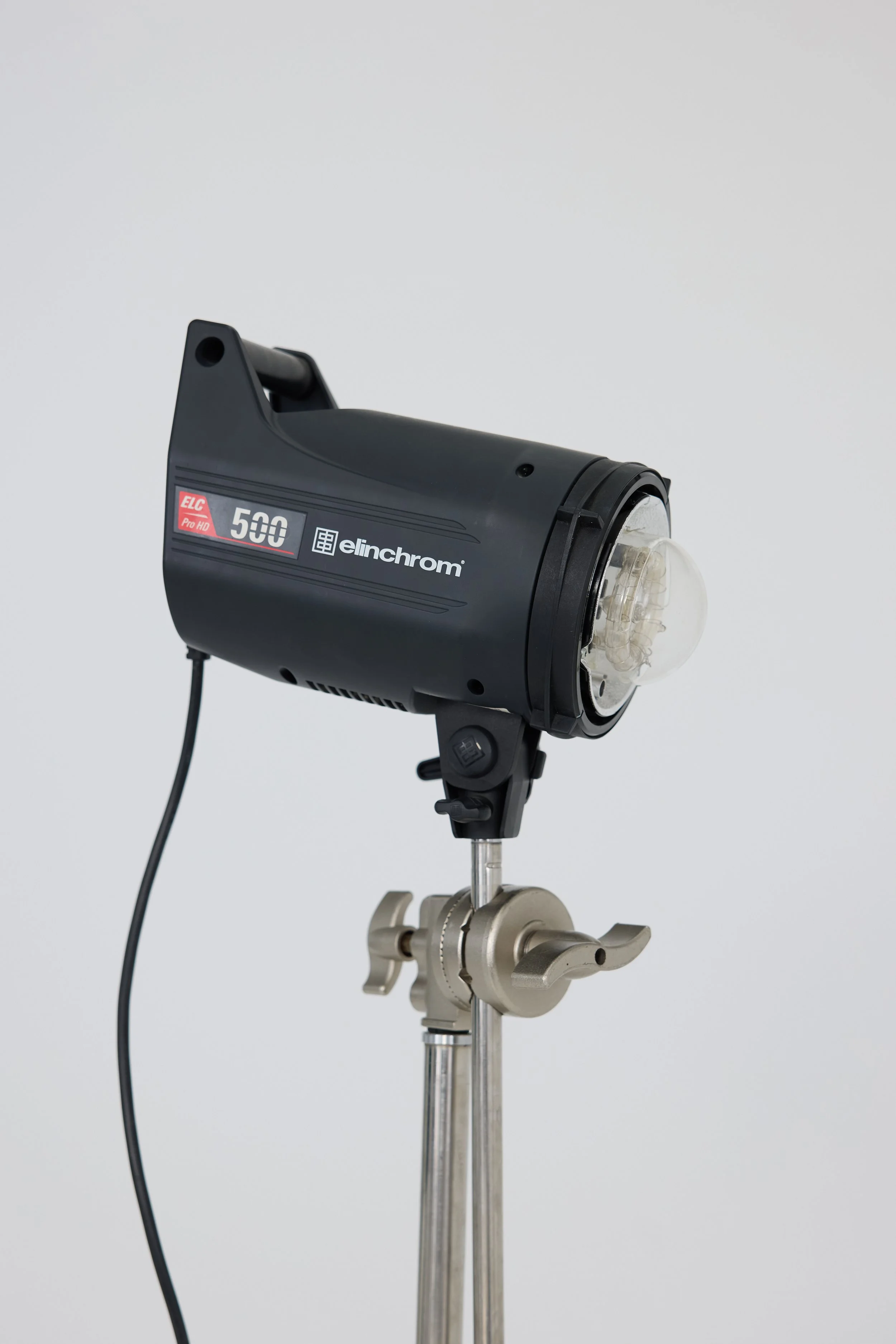 A professional studio light mounted on a stand against a plain white background.