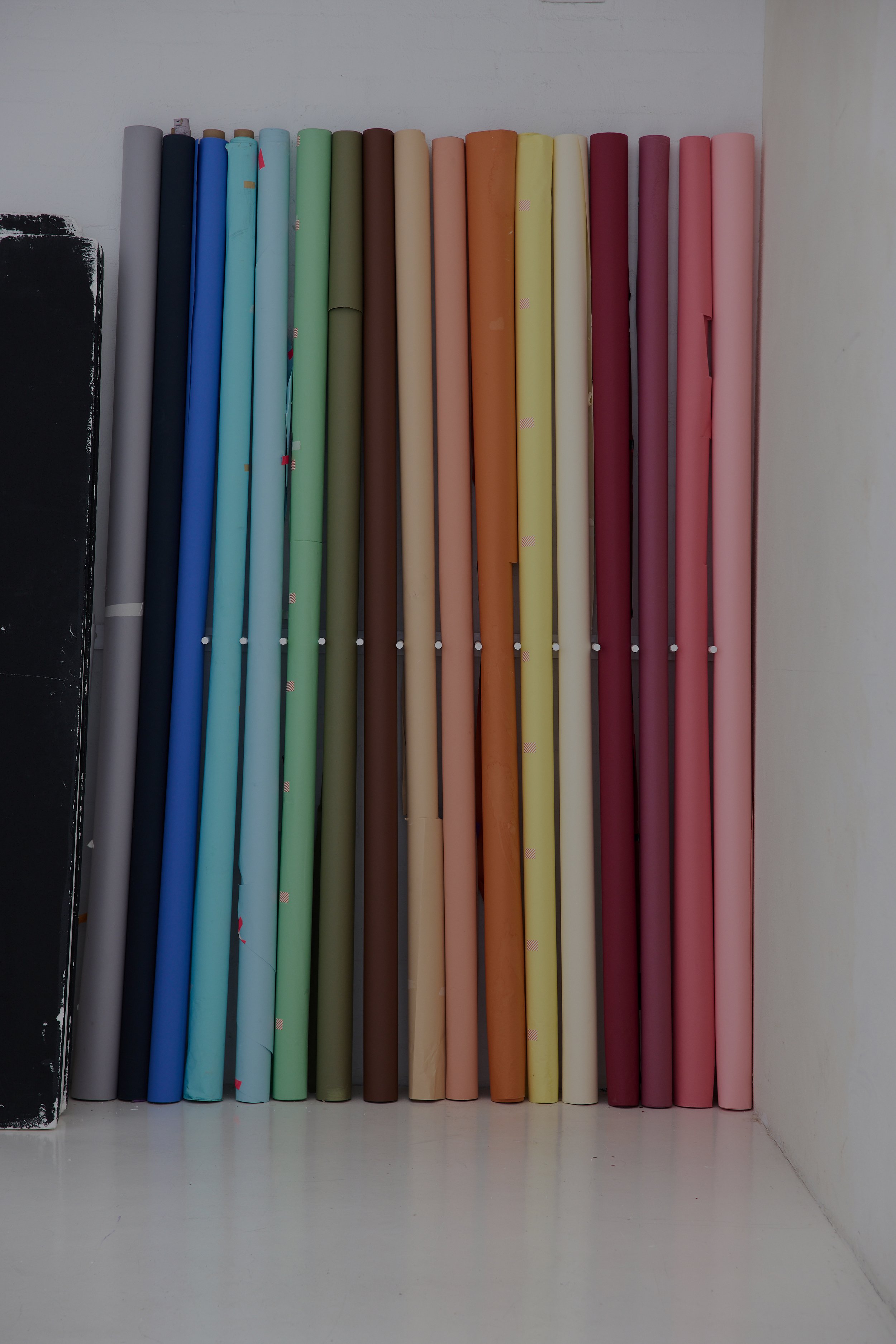 Rolled colourful backdrop paper rolls arranged vertically.