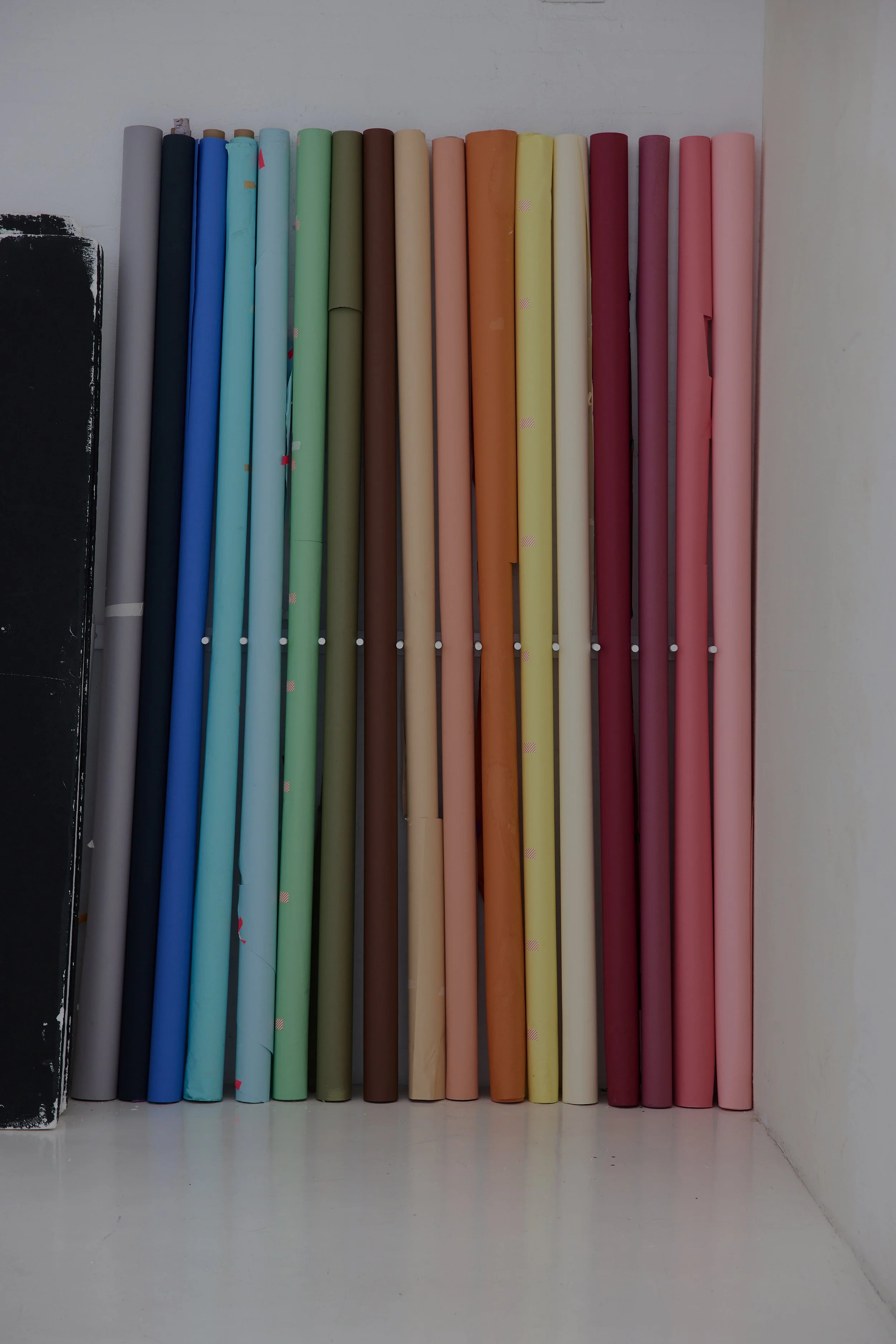 Rolled colourful backdrop paper rolls arranged vertically.