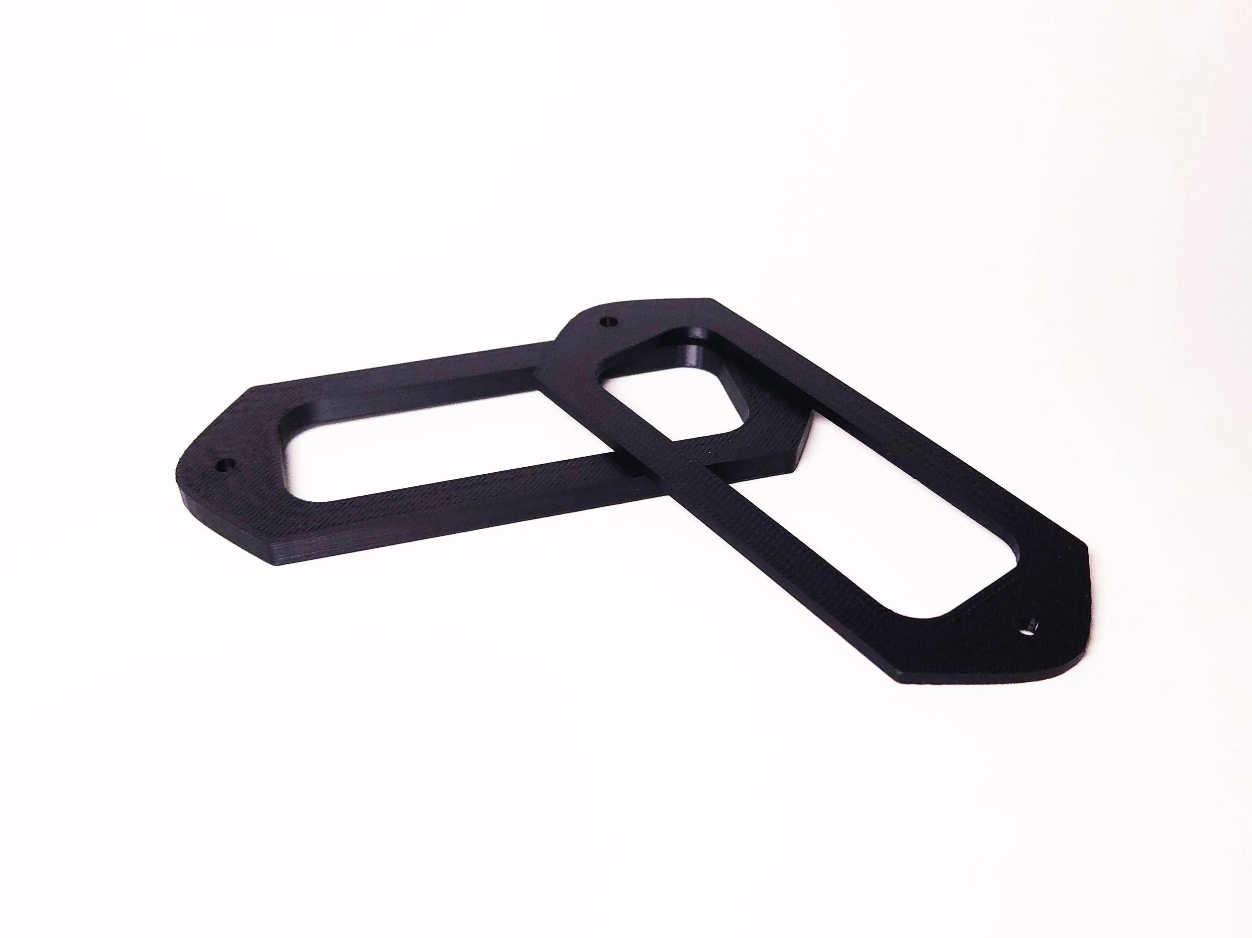 Two black plastic brackets with elongated oval openings, overlapping on a plain white background.