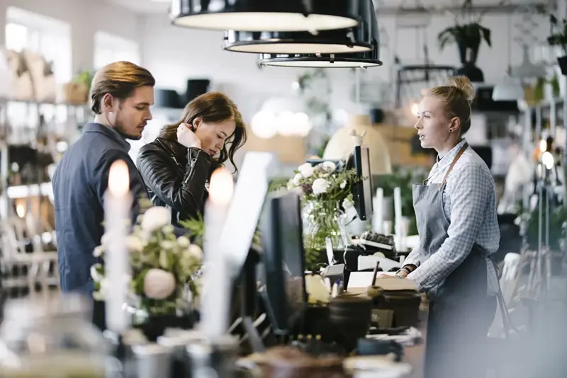 lady at a cafe counter taking down and order for two people.