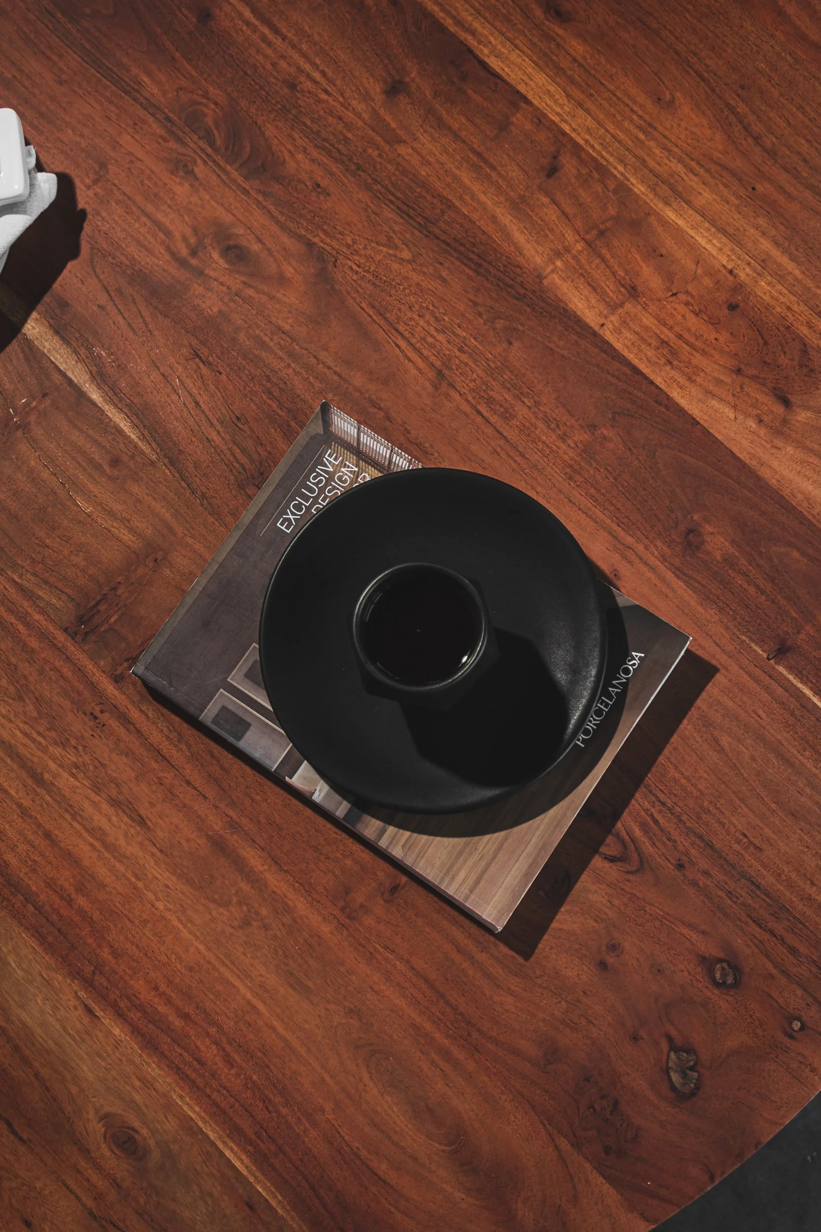 Wooden floor with a dark ceramic vase on a magazine featuring exclusive design styles.