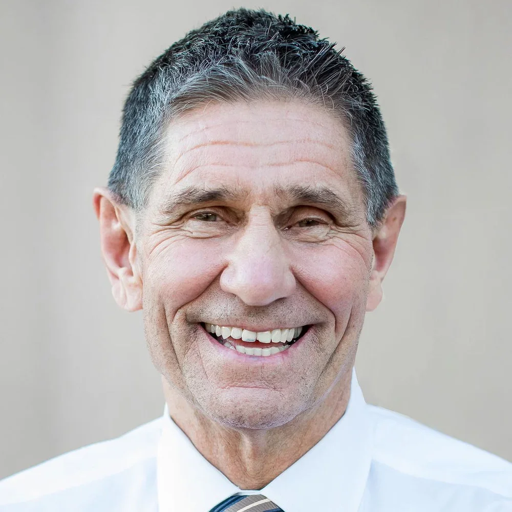 Dr. Mike, a dark haired man wearing a white collared shirt.