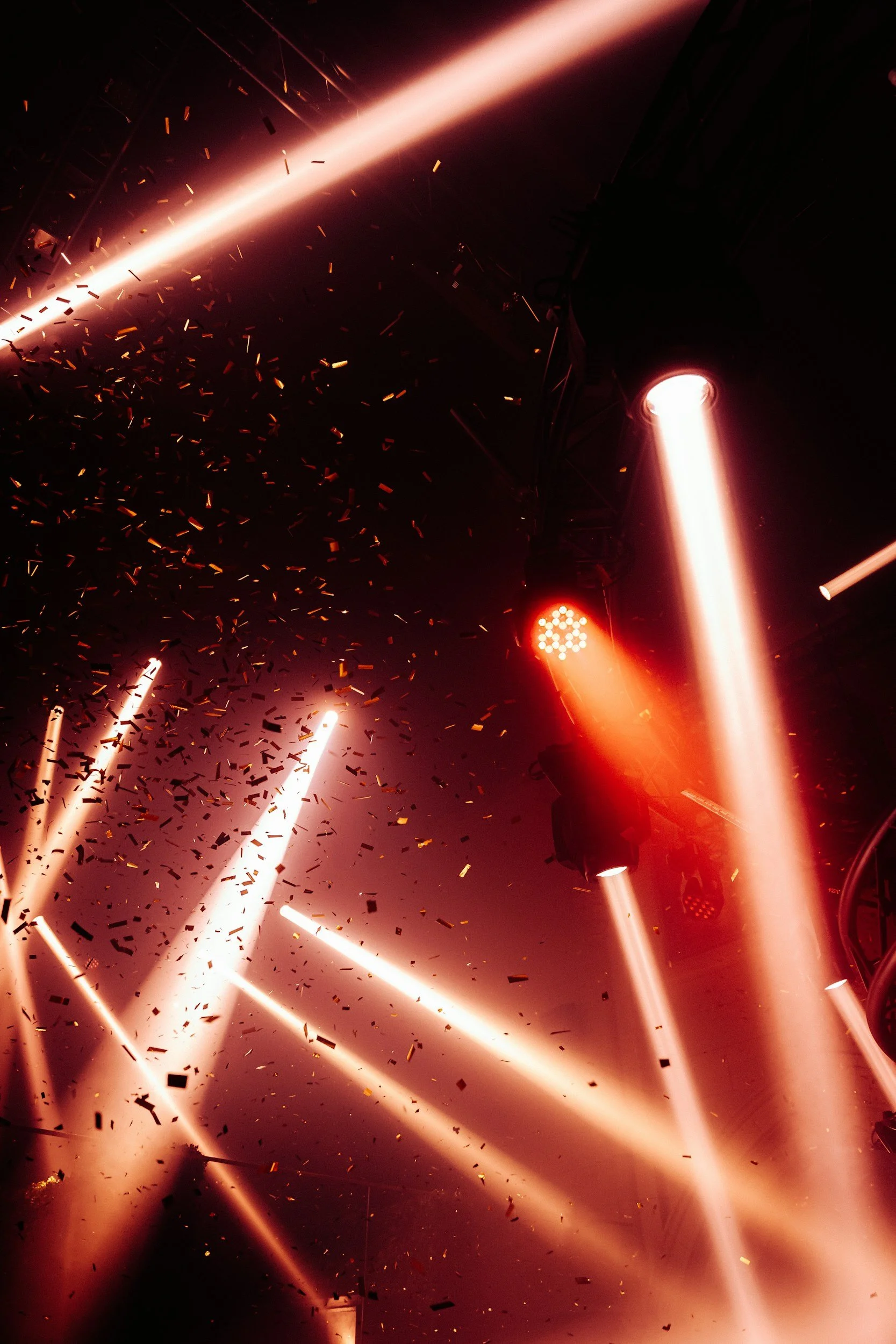 Stage lighting with bright beams and confetti at a concert or event.