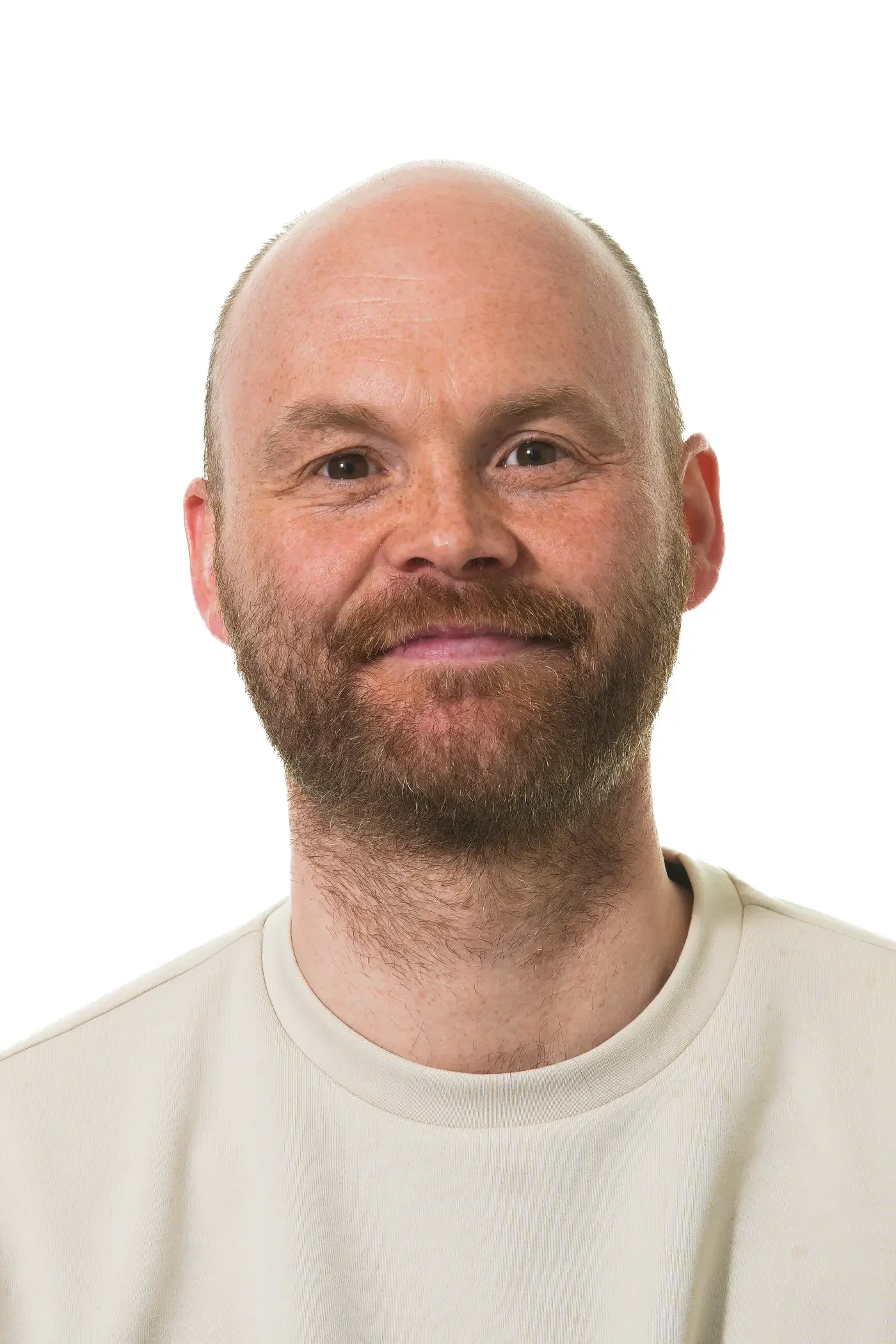 Billedet viser en mand med skaldet hoved, skæg og smilende ansigt iført en sort t-shirt.
