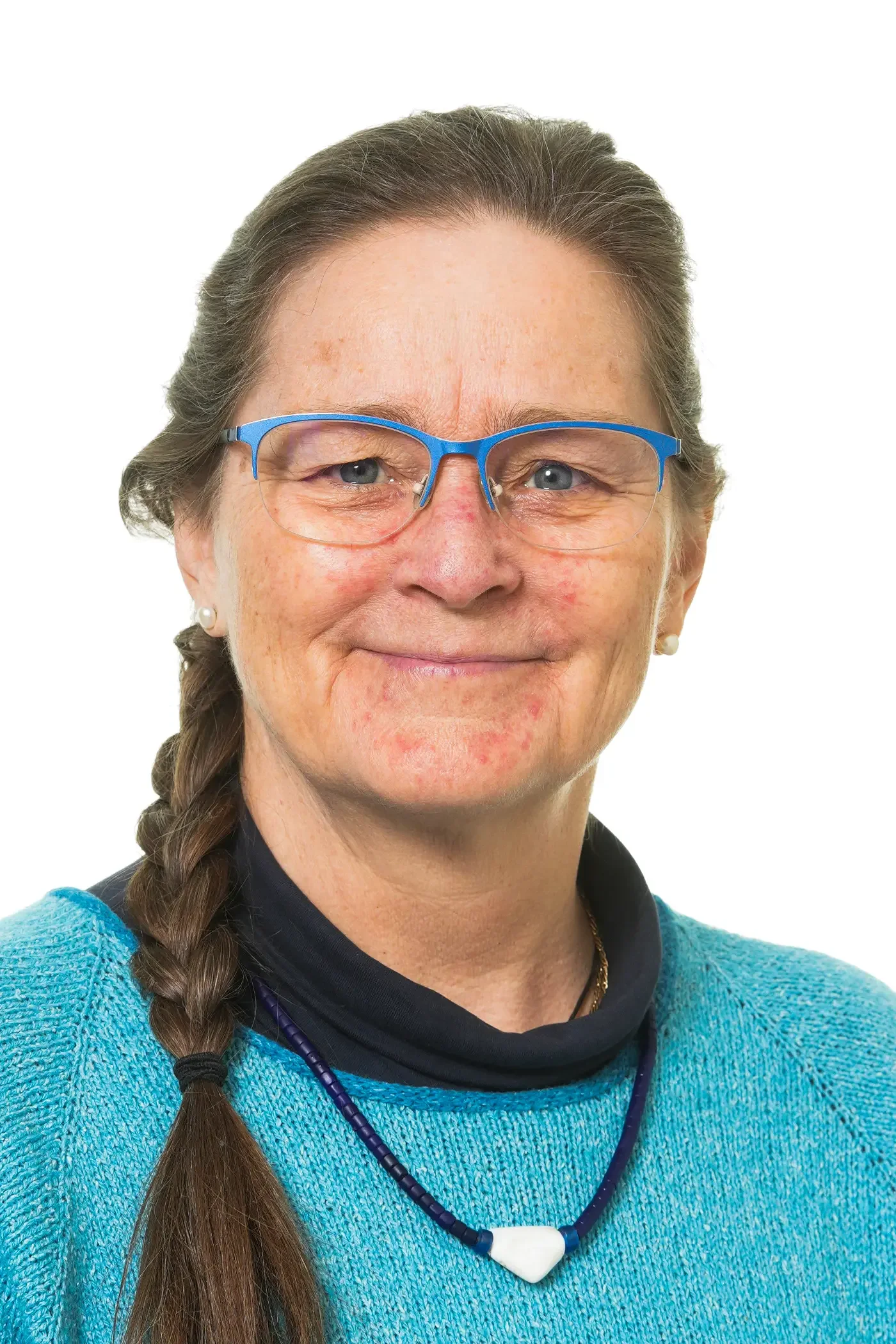 Et smilende ældre kvindemenneske med briller, greyet hår, smilende ansigt, er iført en lyserød T-shirt, har flere halskæder og et armbånd, har lys hud og er set mod en hvid baggrund.