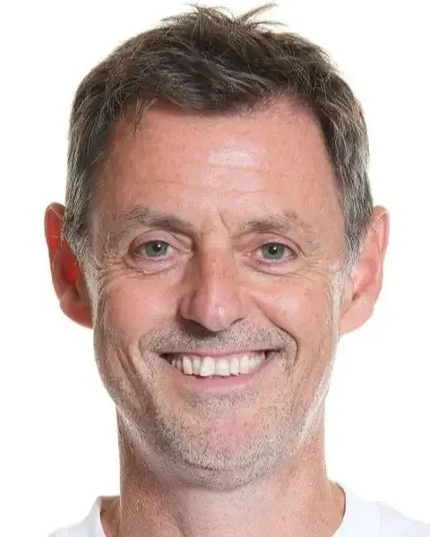 Billedet viser en ældre herre med kort, let gråt hår og et bredt smil, iført en hvid t-shirt. Gorm den gamle.