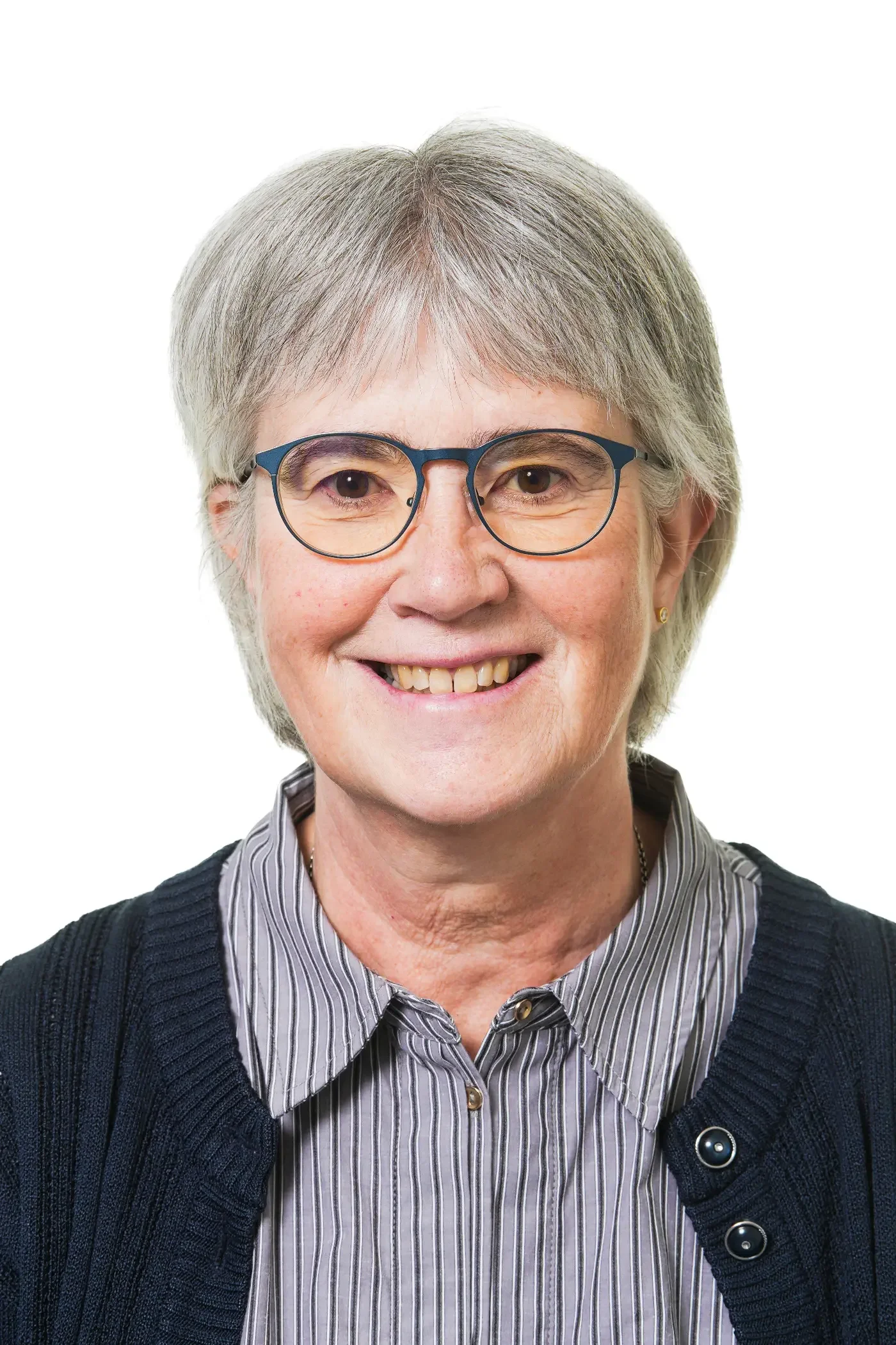 Et nærbillede af en ældre kvinde med gråt hår, briller og farverigt tørklæde foran en hvid baggrund.