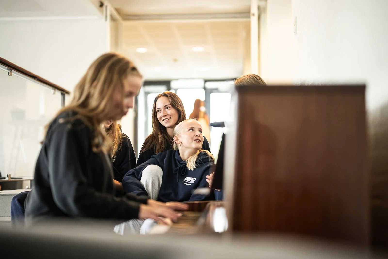 En gruppe unge piger sidder ved en computer i et indendørs rum, nogle af dem smiler og ser opmærksomt på skærmen.