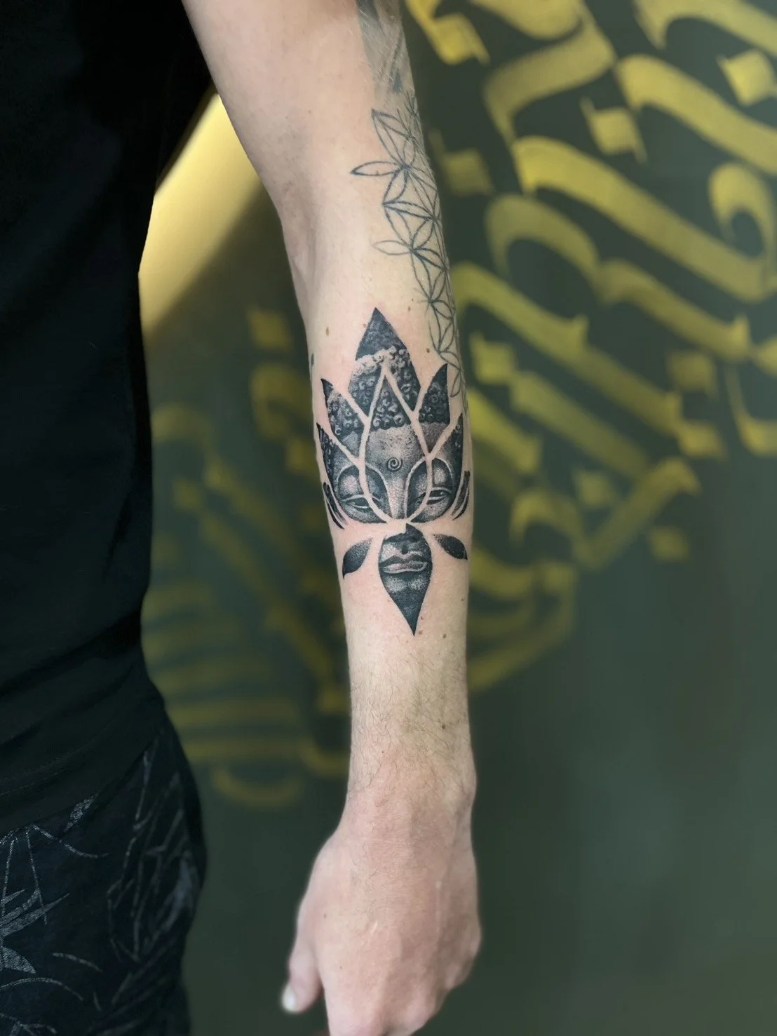 Black tattoo of a woman's face with leaves and geometric patterns on the arm.