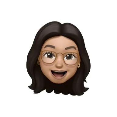 An animated emoji of a woman freelance web designer with dark hair, glasses, and earrings, smiling with an open mouth.