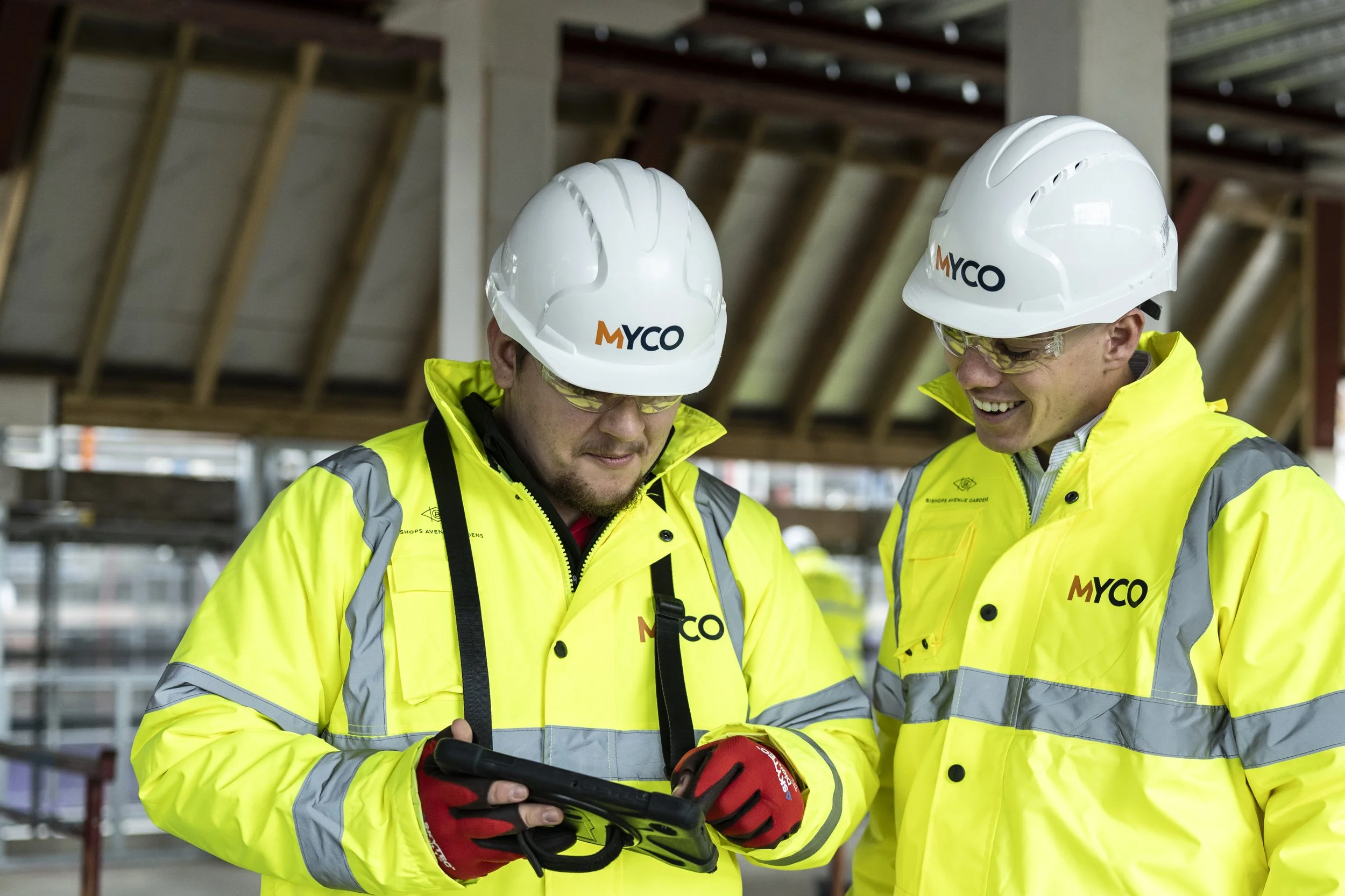 Group of seven people standing in front of a sign that reads 'MYCO' with modern residential buildings in the background.