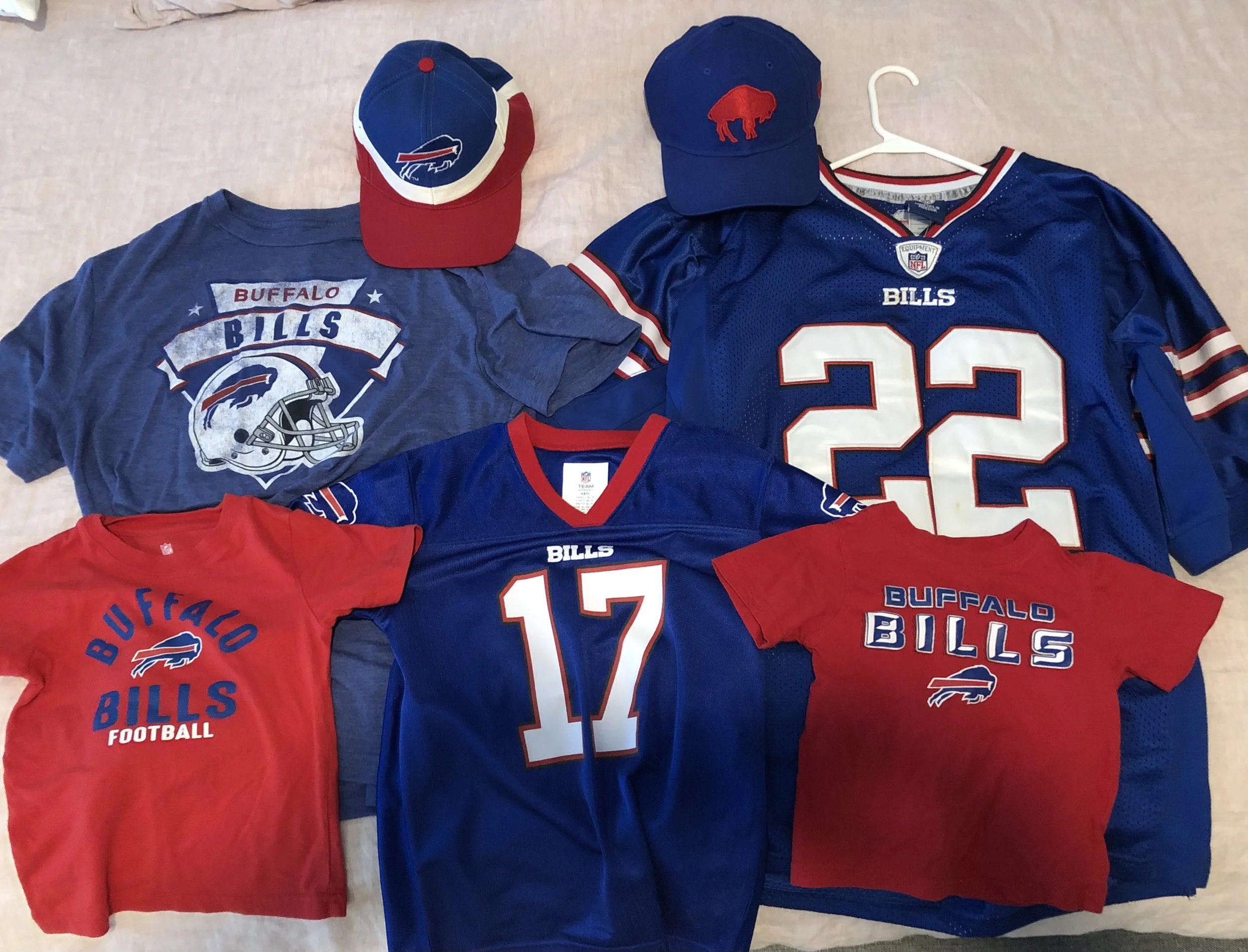 Buffalo Bills football team memorabilia including two jerseys, one red and one blue, two caps with Bills logos, and a T-shirt with Bills logo.