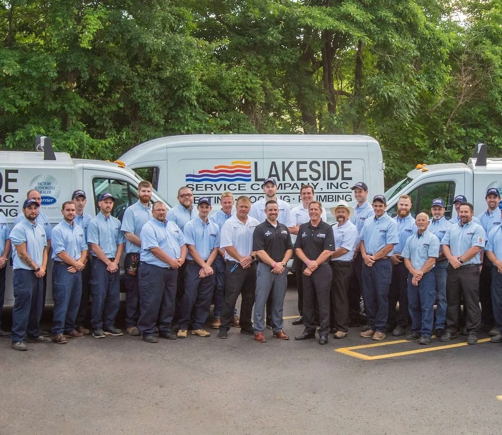 Group of workers standing in front of service trucks with the Lakeside Service Cover Company logo, posing for a group photo outdoors.