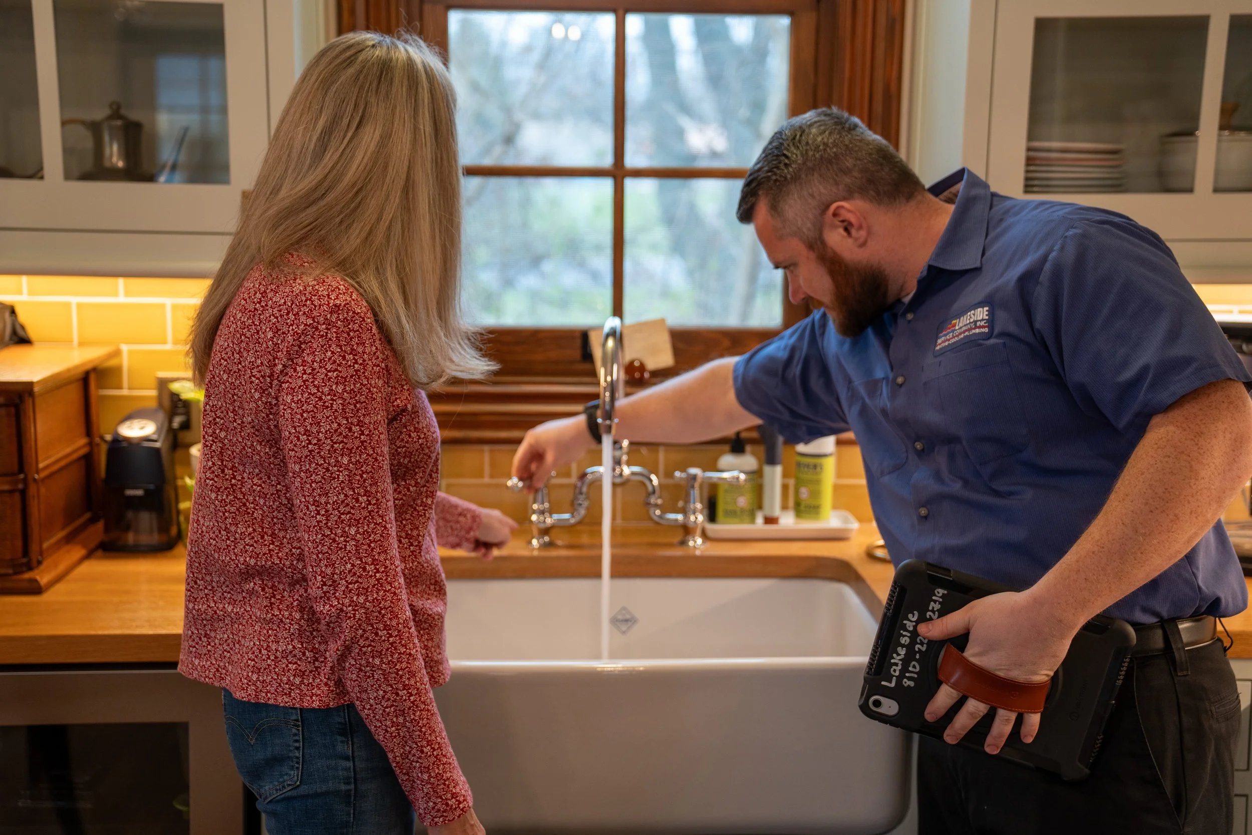 Lakeside plumber checking a kitchen faucet with a homeowner