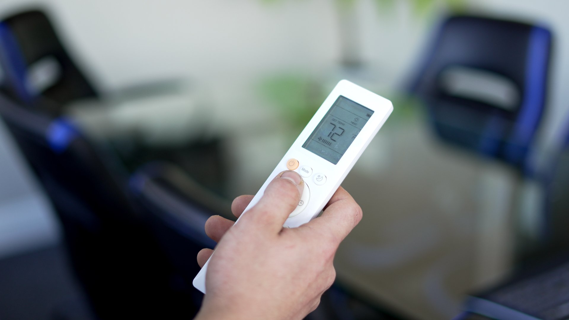 HVAC technician holding AC remote control for home cooling system in Southeast Michigan