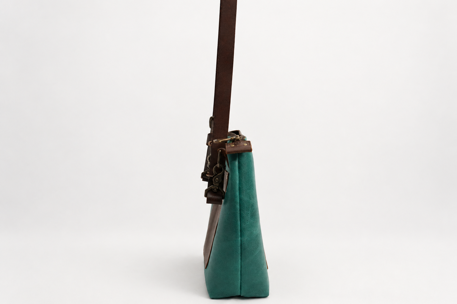 Teal crossbody bag on seamless backdrop-4.png