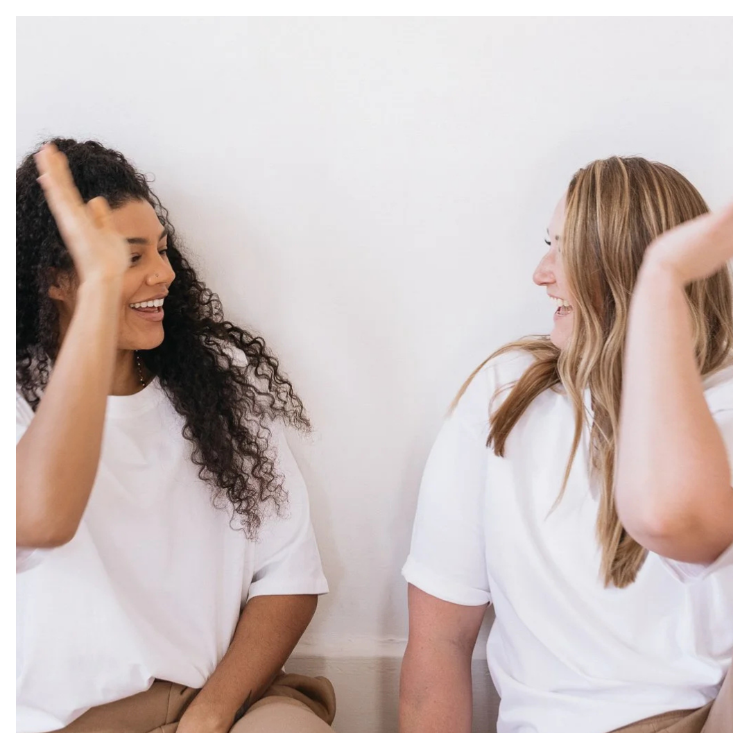Two women smiling and high-fiving during a conversation at Remedy Functional Medicine.