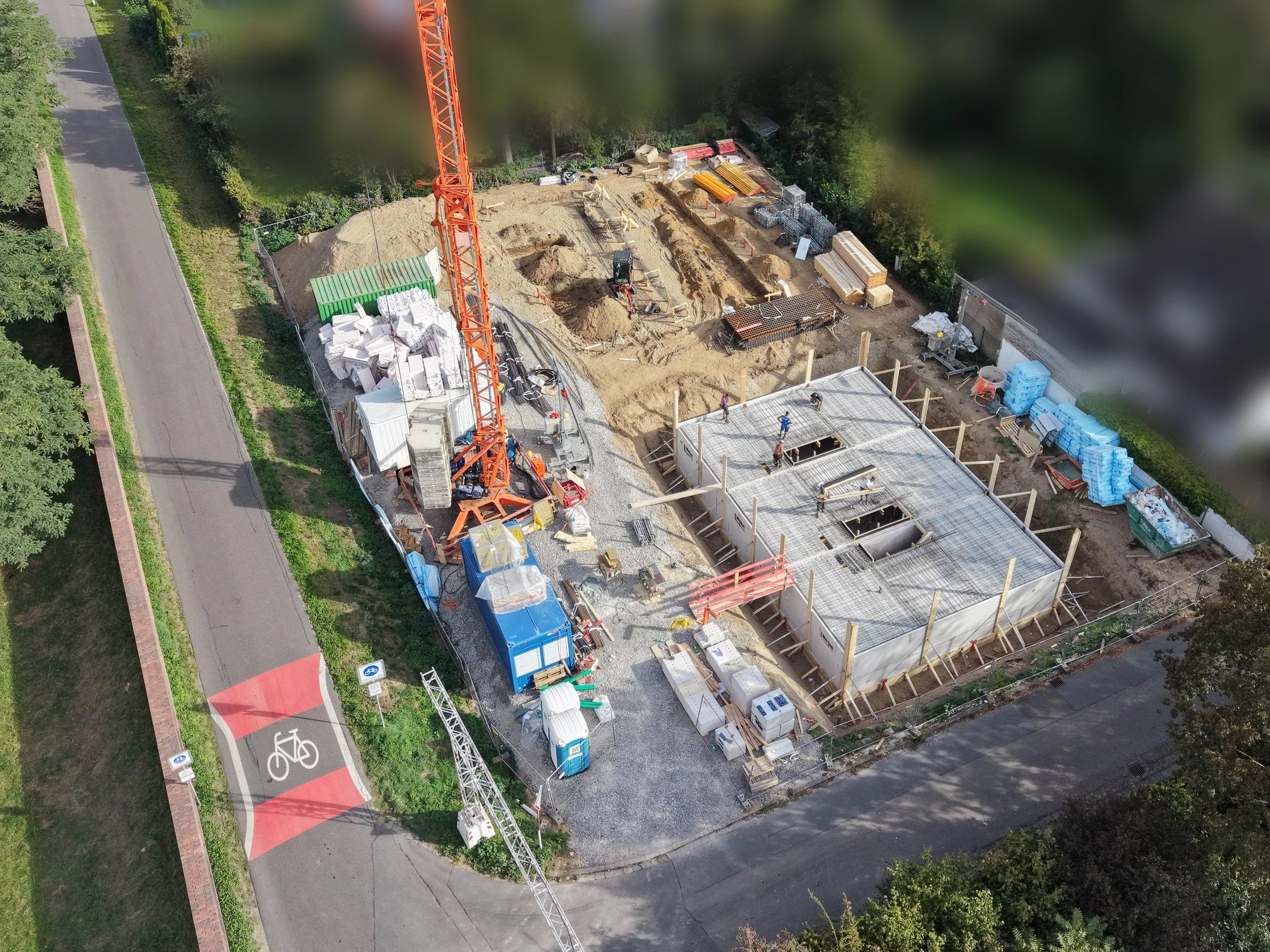 Luftbild der Baustelle Rheinblick Dormagen in Stürzelberg mit Kran, Kellergeschoss und Rheindeich, Neubau von Reihenhäusern nach KfW 40 QNG