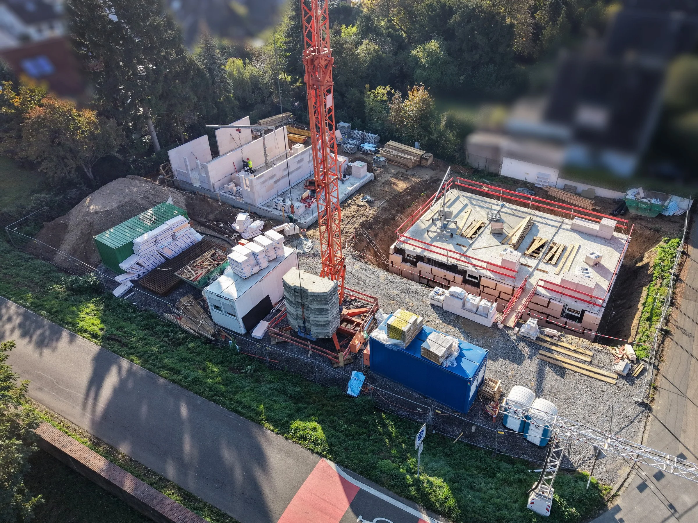 Luftbild der Baustelle Rheinblick Dormagen in Stürzelberg mit Kran, ersten Erdgeschosswänden aus Kalksandstein und Rheindeich, Neubau von Reihenhäusern nach KfW 40 QNG