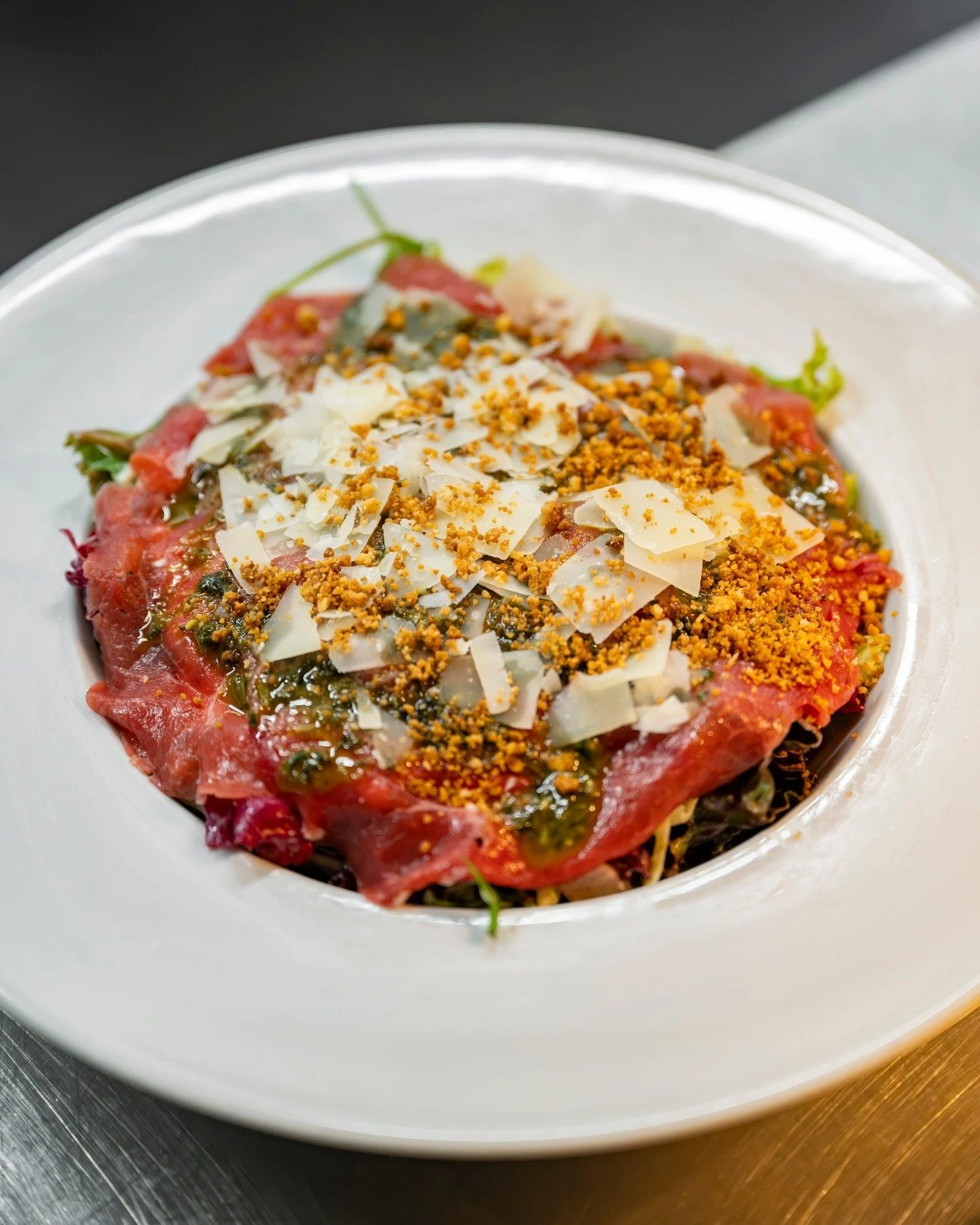 Bijblijven doe je met een klassieker die blijft verrassen.

Onze carpaccio krijgt een eigen twist met cr&egrave;me van truffel, huisgemaakte pesto, grove Parmezaan en een crumble van cashew en hazelnoot. Vol van smaak, mooi in balans en precies goed 