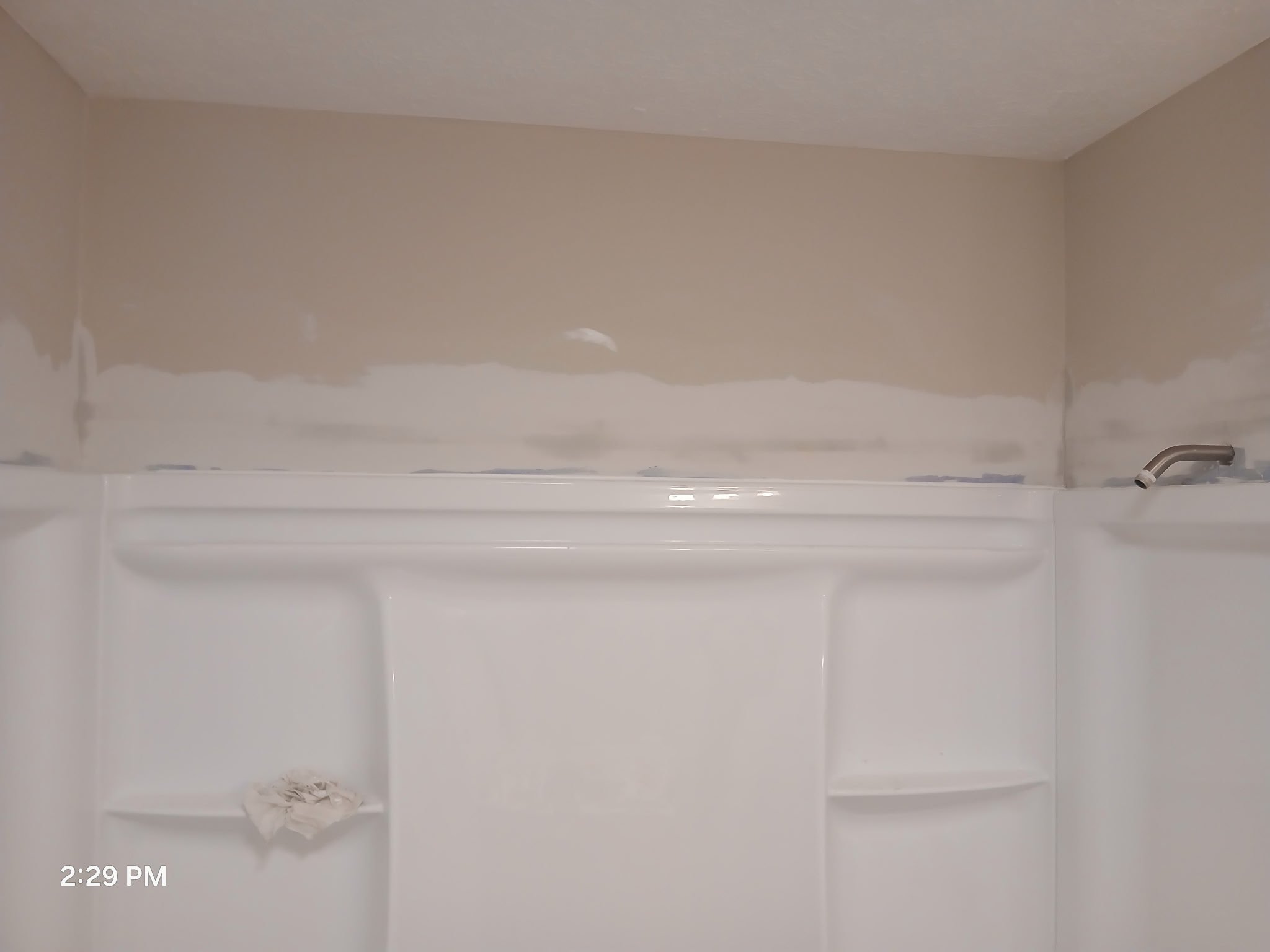 Bathroom shower area with drywall drywall walls still needing paint or finishing, a white shower stall with shelves, and a brown drywall ceiling.
