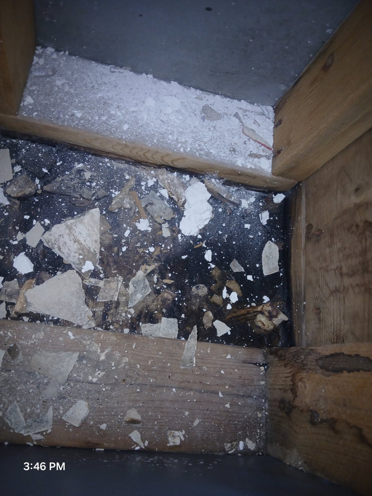 Floor with debris and drywall dust inside a wooden corner of a construction or renovation site.