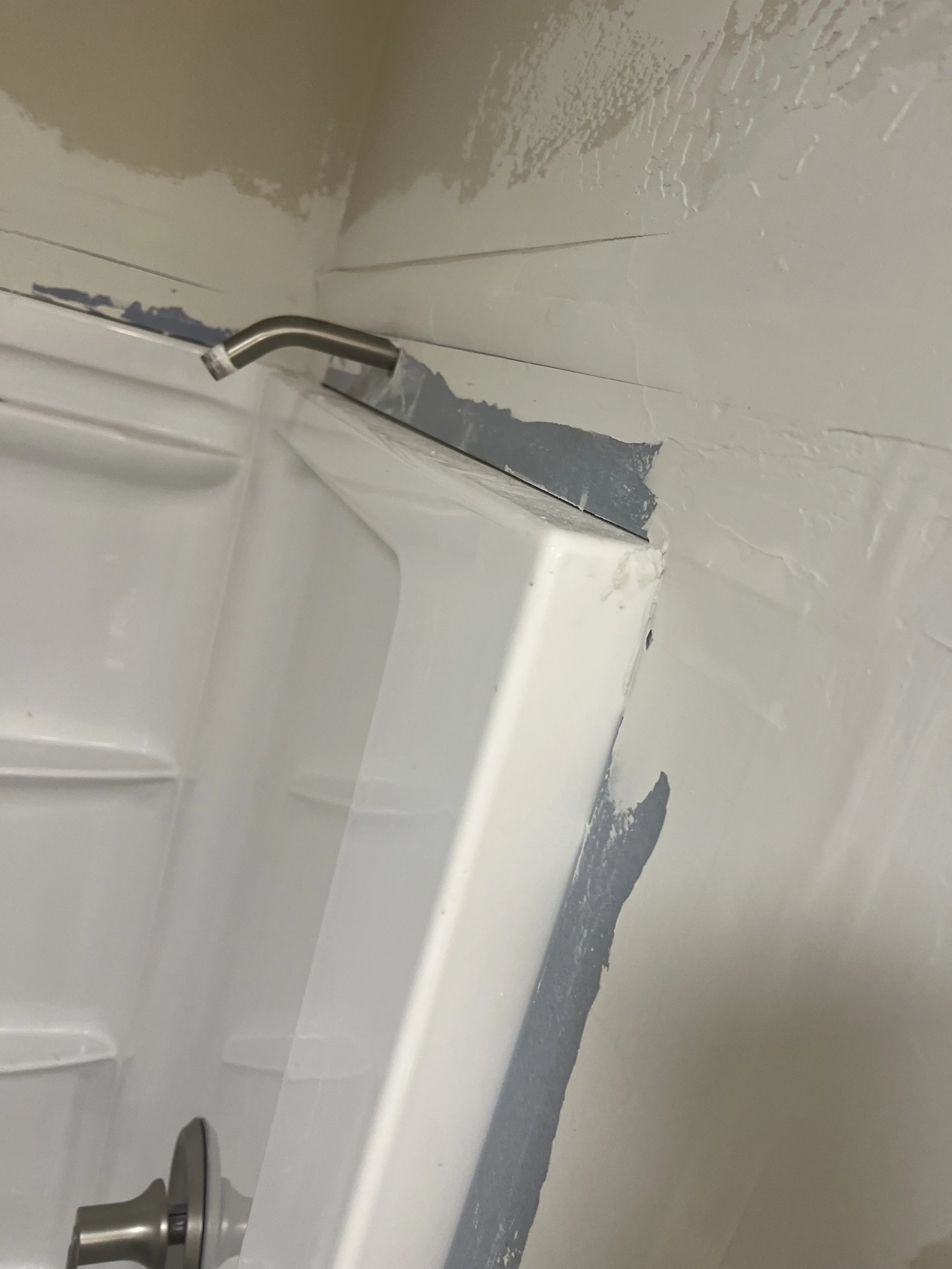 Close-up of a damaged drywall and trim around a kitchen sink. The drywall paint is chipped, revealing a darker layer underneath, with a stainless steel faucet visible.