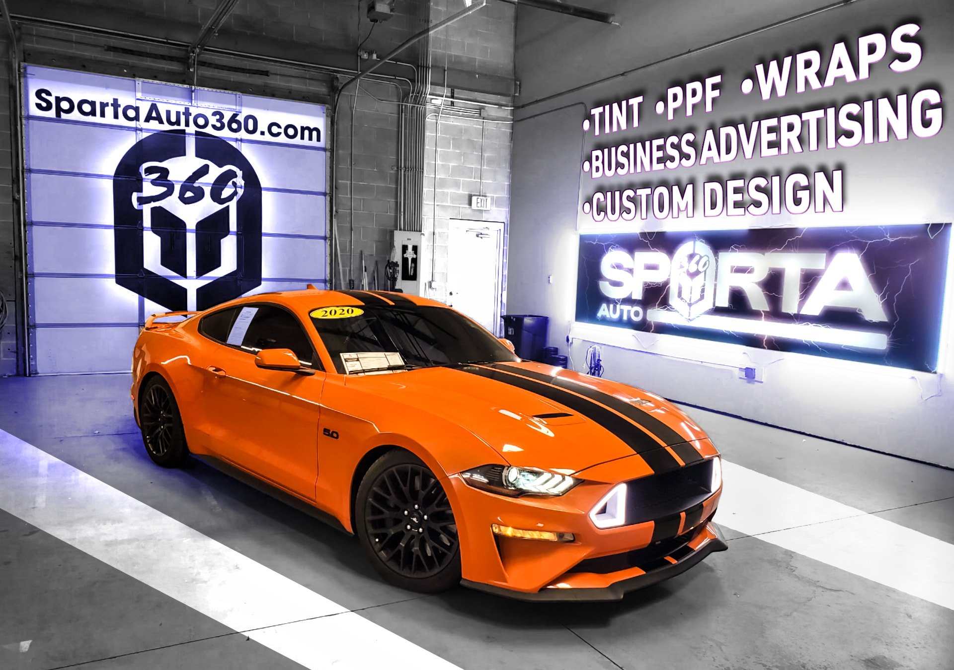 An orange 2020 Ford Mustang with black racing stripes is parked inside a garage at Sparta Auto 360, which offers services like tint, PPF, wraps, business advertising, and custom design. The garage features signage and lighting emphasizing automotive