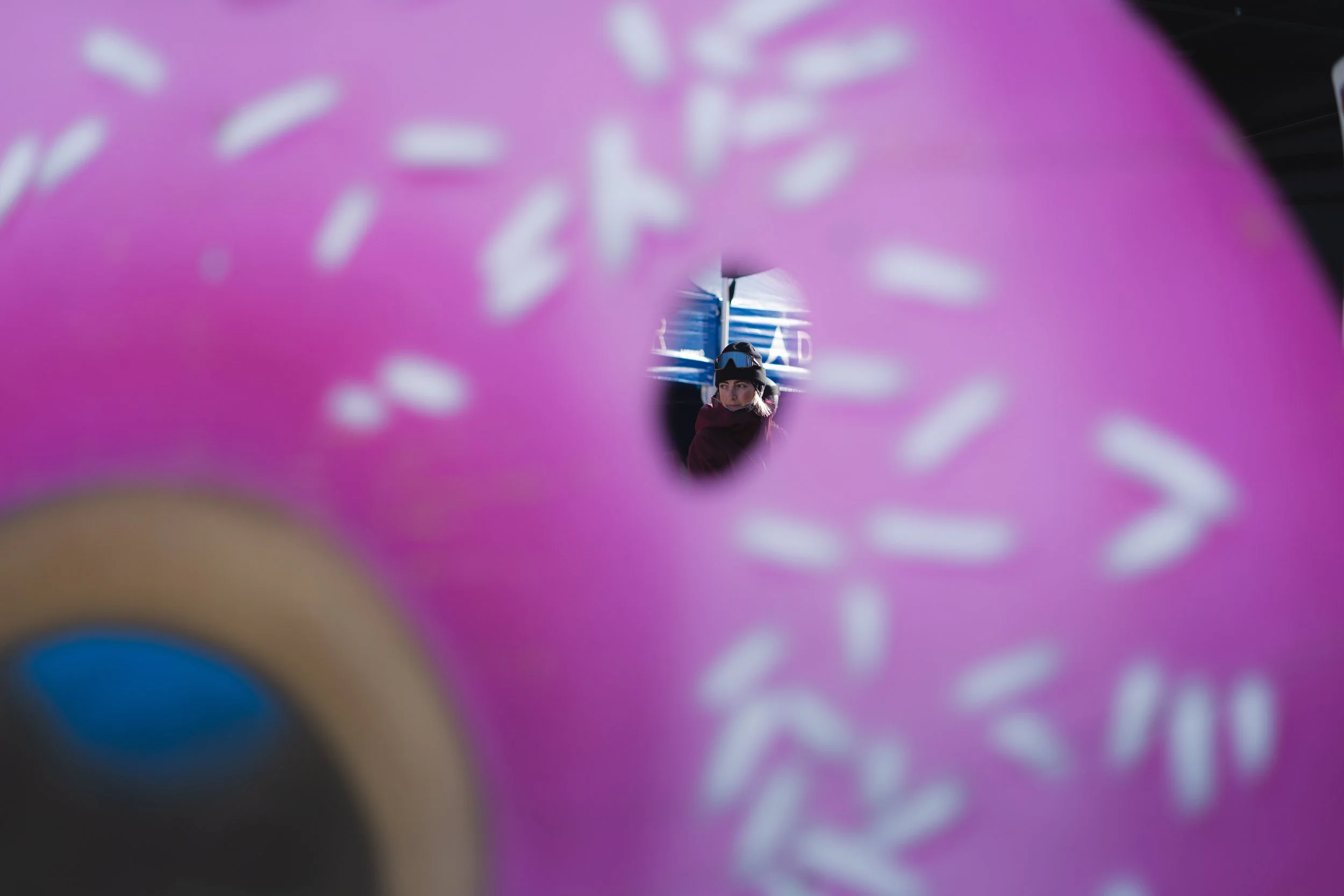 Vue à travers un beignet rose avec une personne floue en arrière-plan.