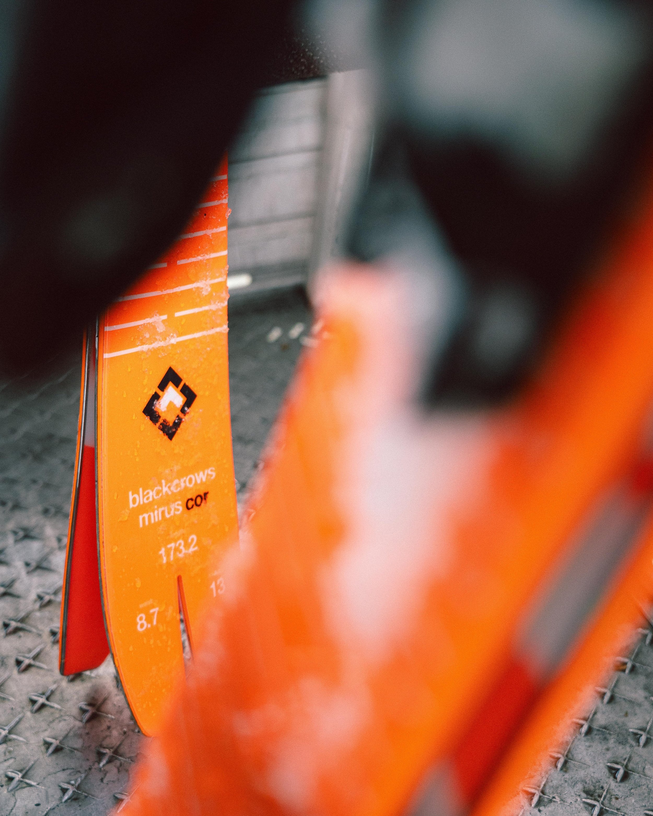 Deux skis orange "blackcrows mirus cor" avec de la neige fondue.
