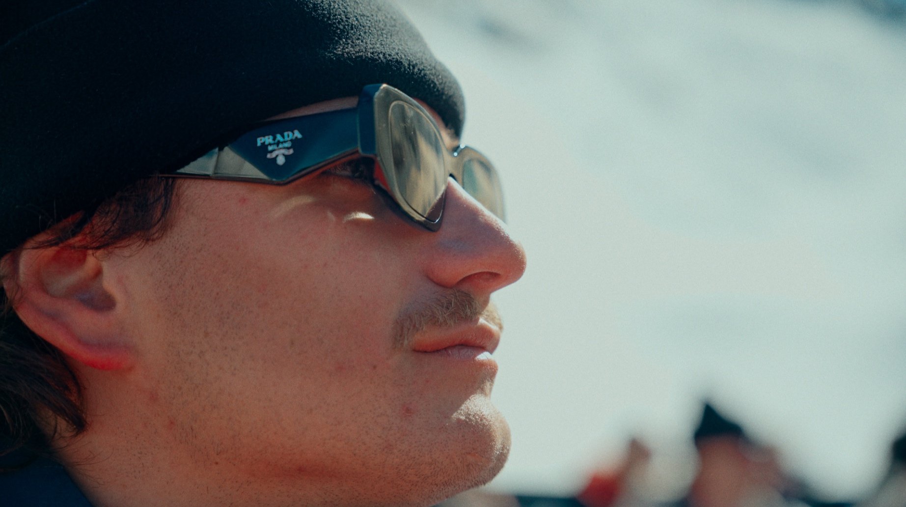 Homme portant des lunettes de soleil Prada et un bonnet noir.