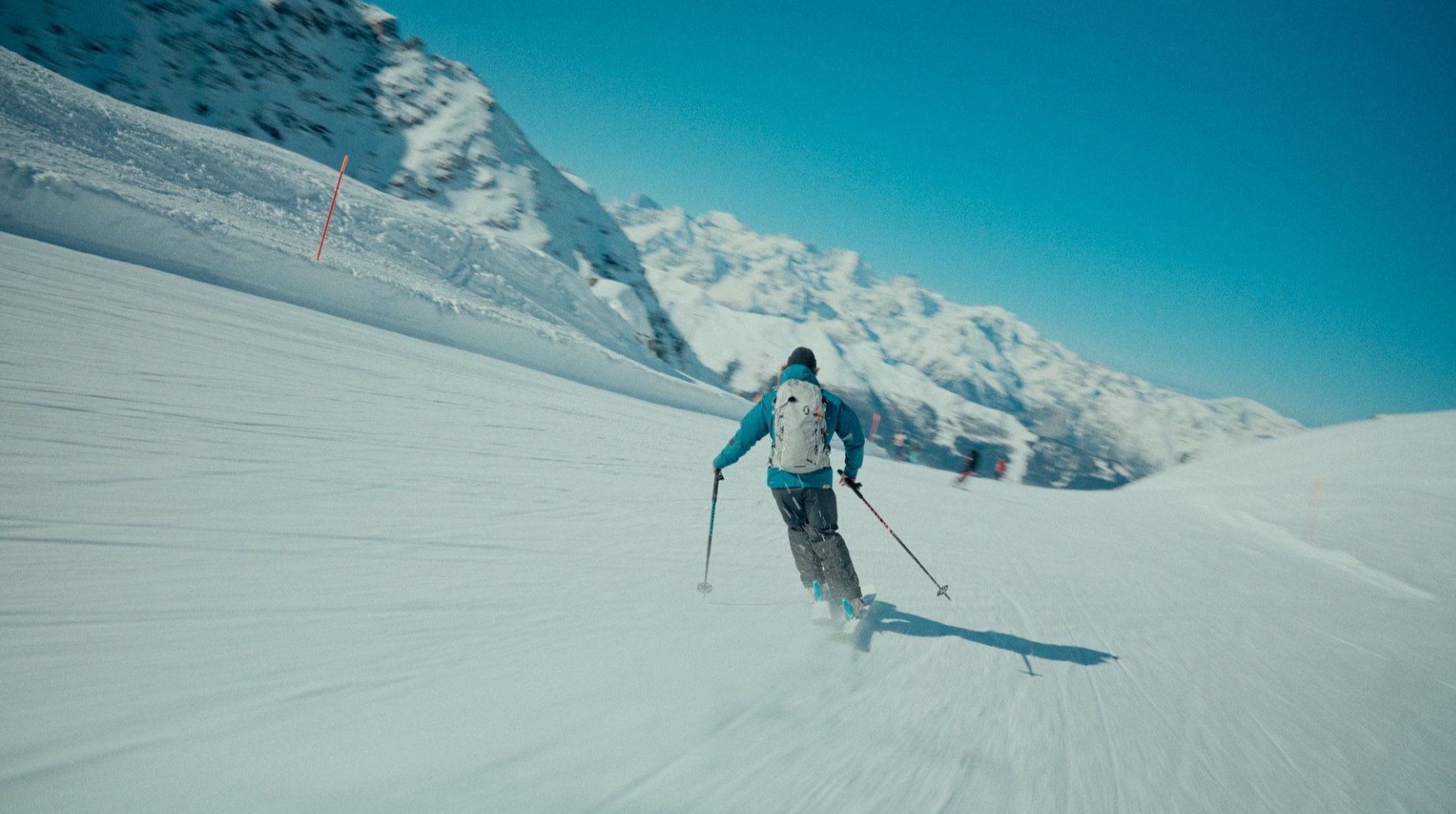 Skieur sur une piste enneigée dans les montagnes avec ciel bleu.