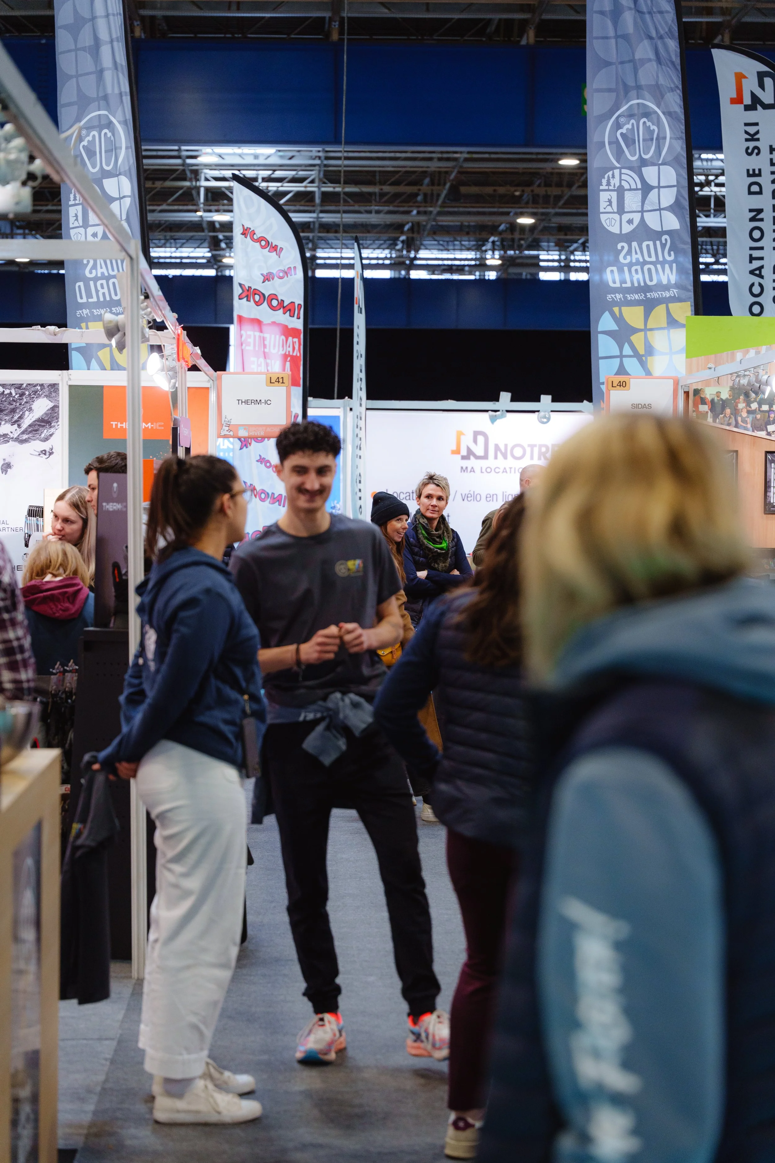 Des personnes discutant dans une exposition avec des stands et des bannières