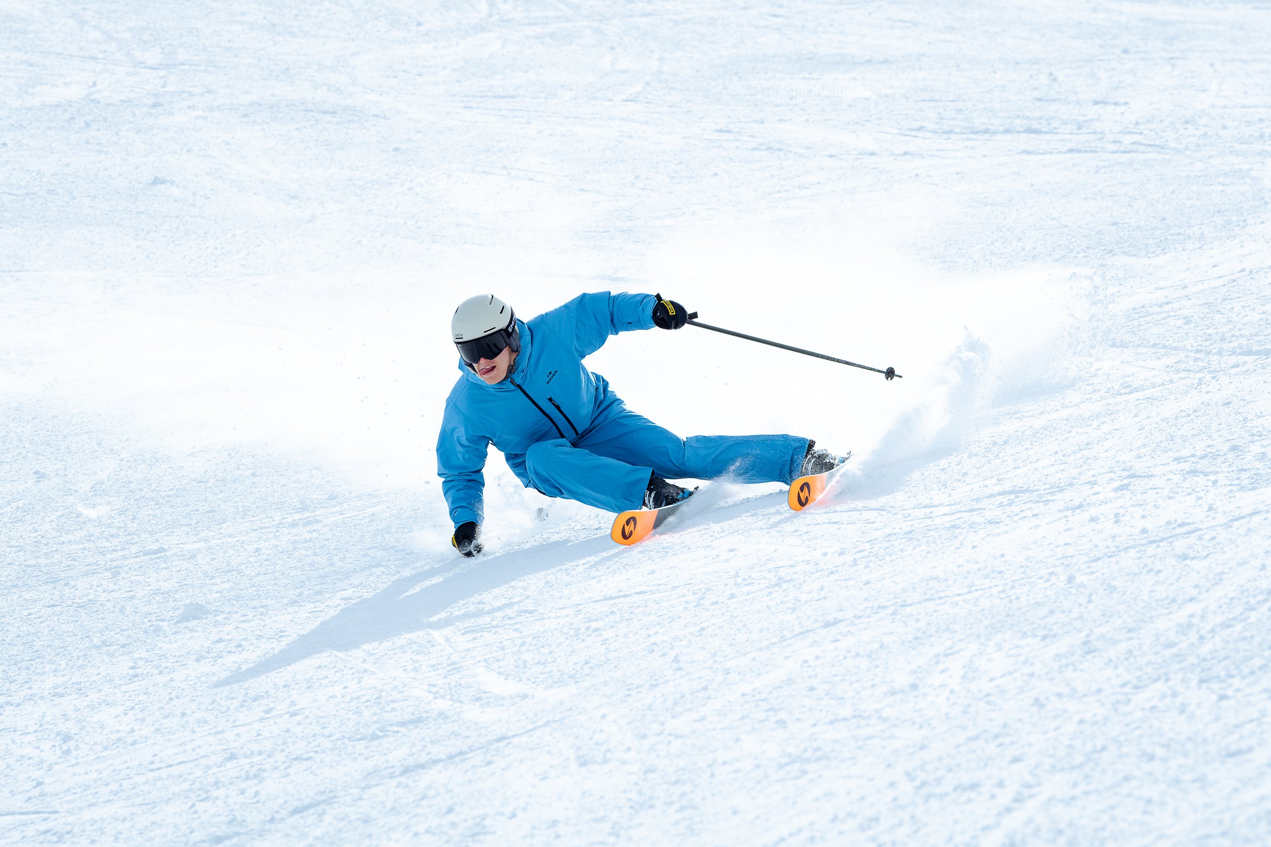 Skieur en tenue bleue skiant sur une pente enneigée.