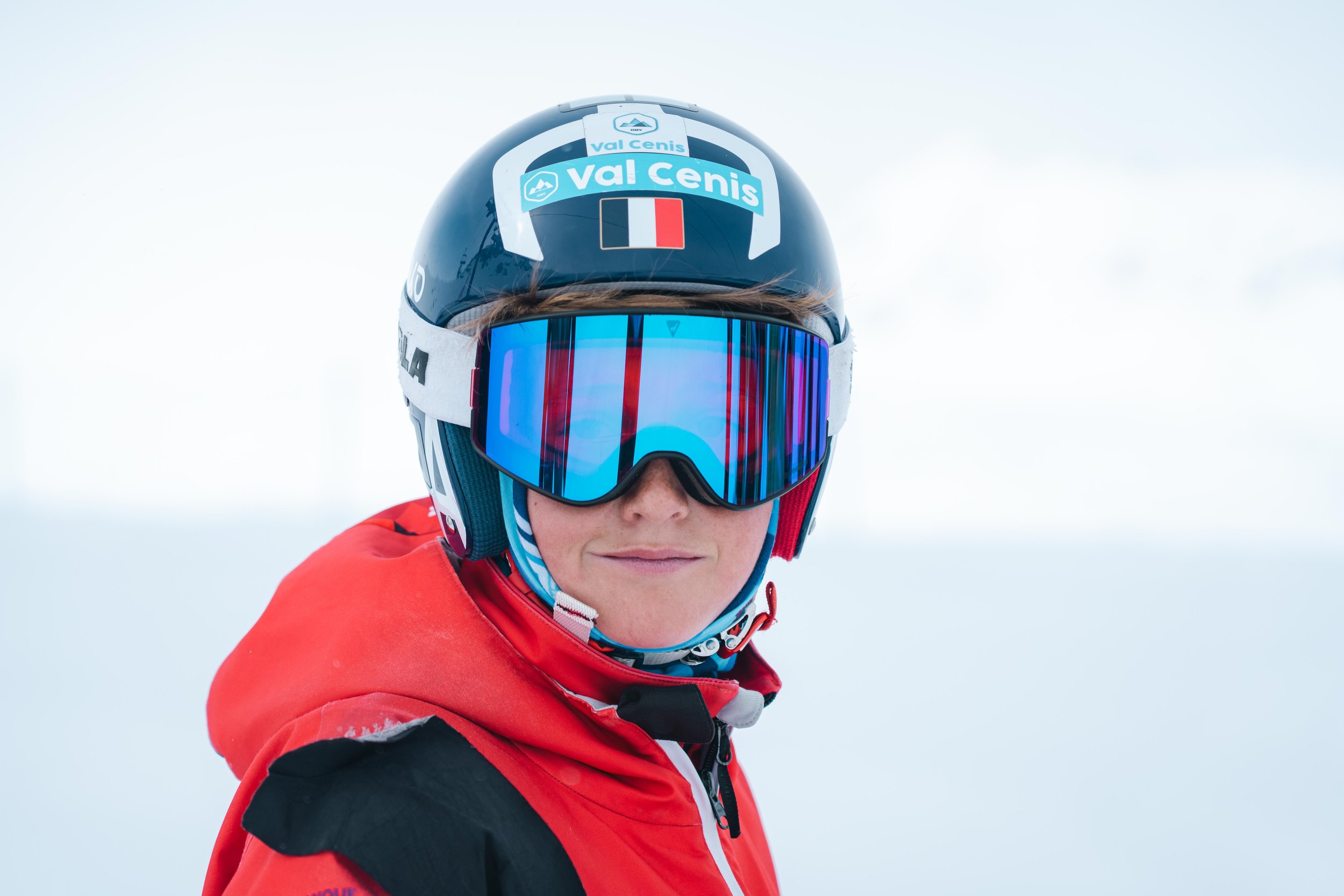 Personne en tenue de ski avec casque "Val Cenis" et lunettes de protection. Plan arrière neigeux.